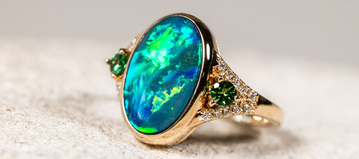 The October birthstone opal set in a yellow gold ring with green gemstones