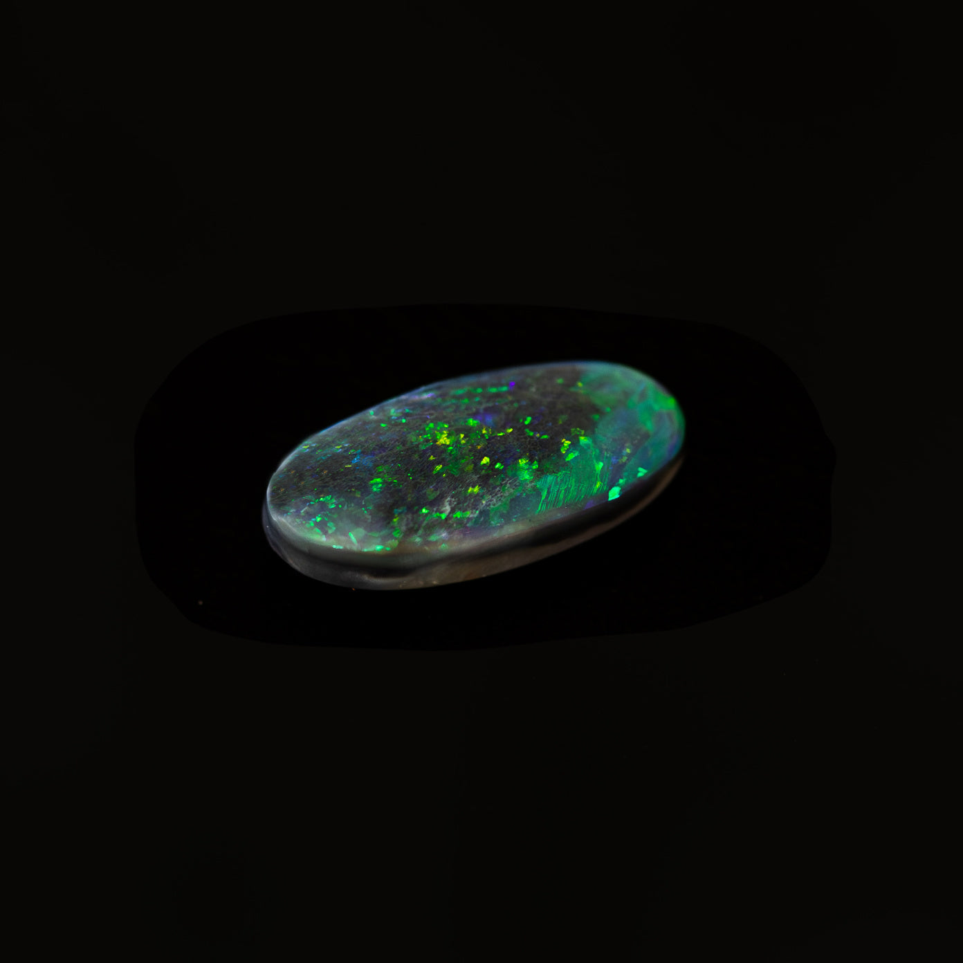 Natural oval-shaped black opal from Lightning Ridge, Australia with green pinfire pattern