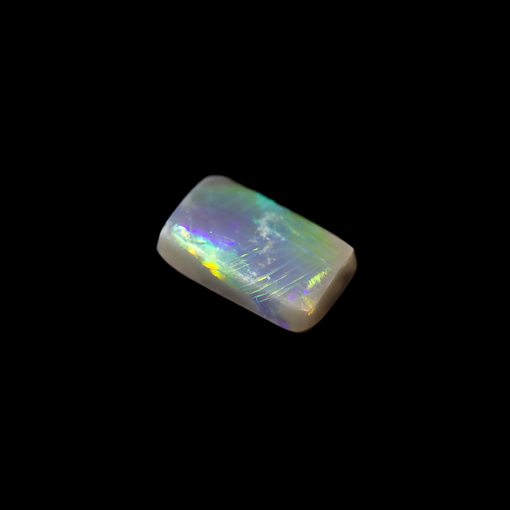 Australian semi-black opal in rectangular cut with bright green pinfire pattern