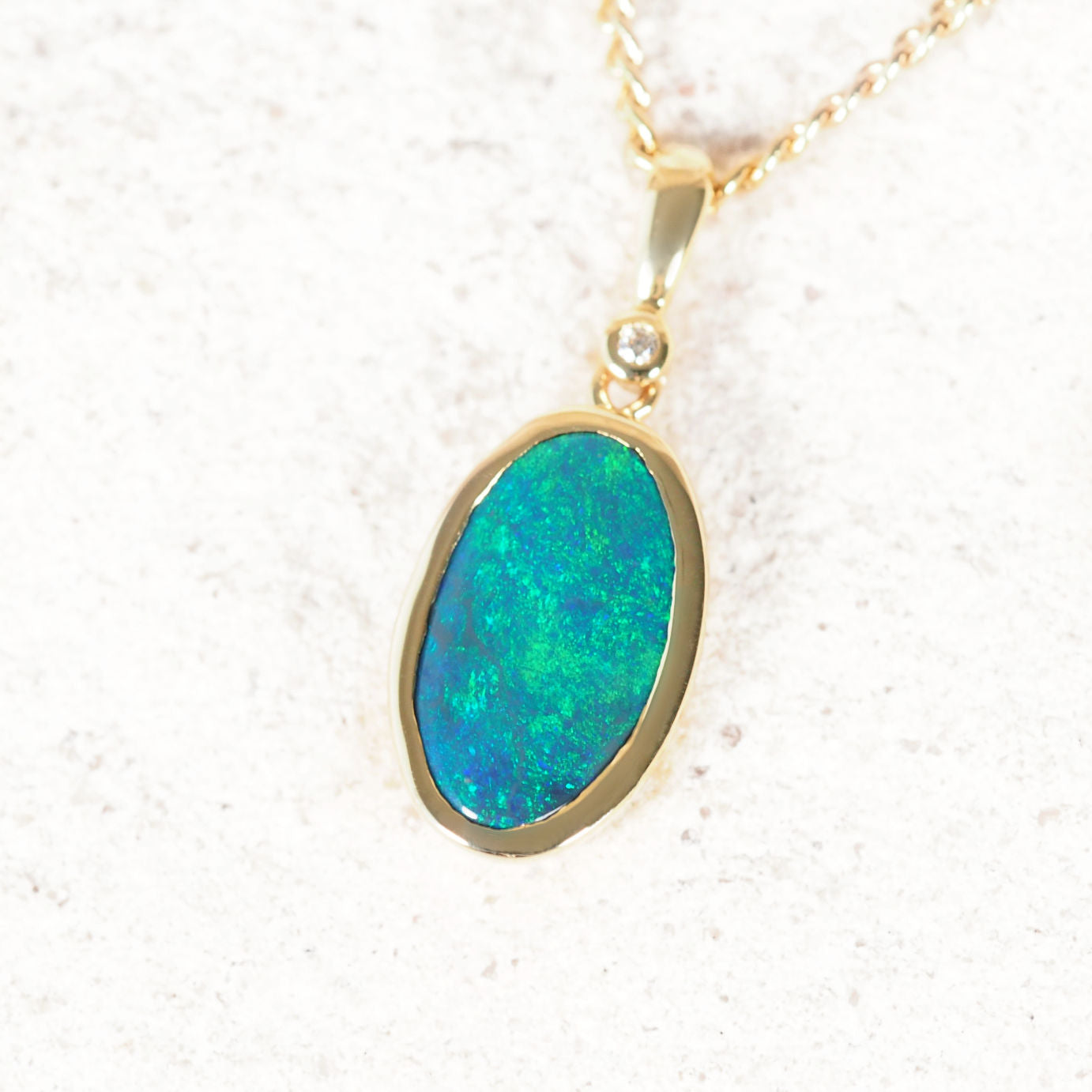 Oval black opal necklace showing green sheen in 14ct yellow gold setting