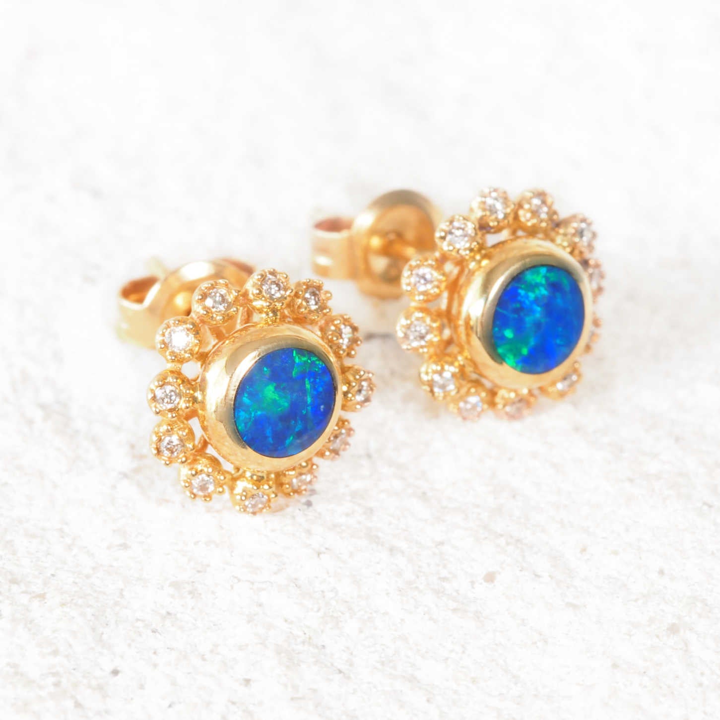 Round Australian opal stud earrings in 14ct yellow gold with sparkling diamond accents.