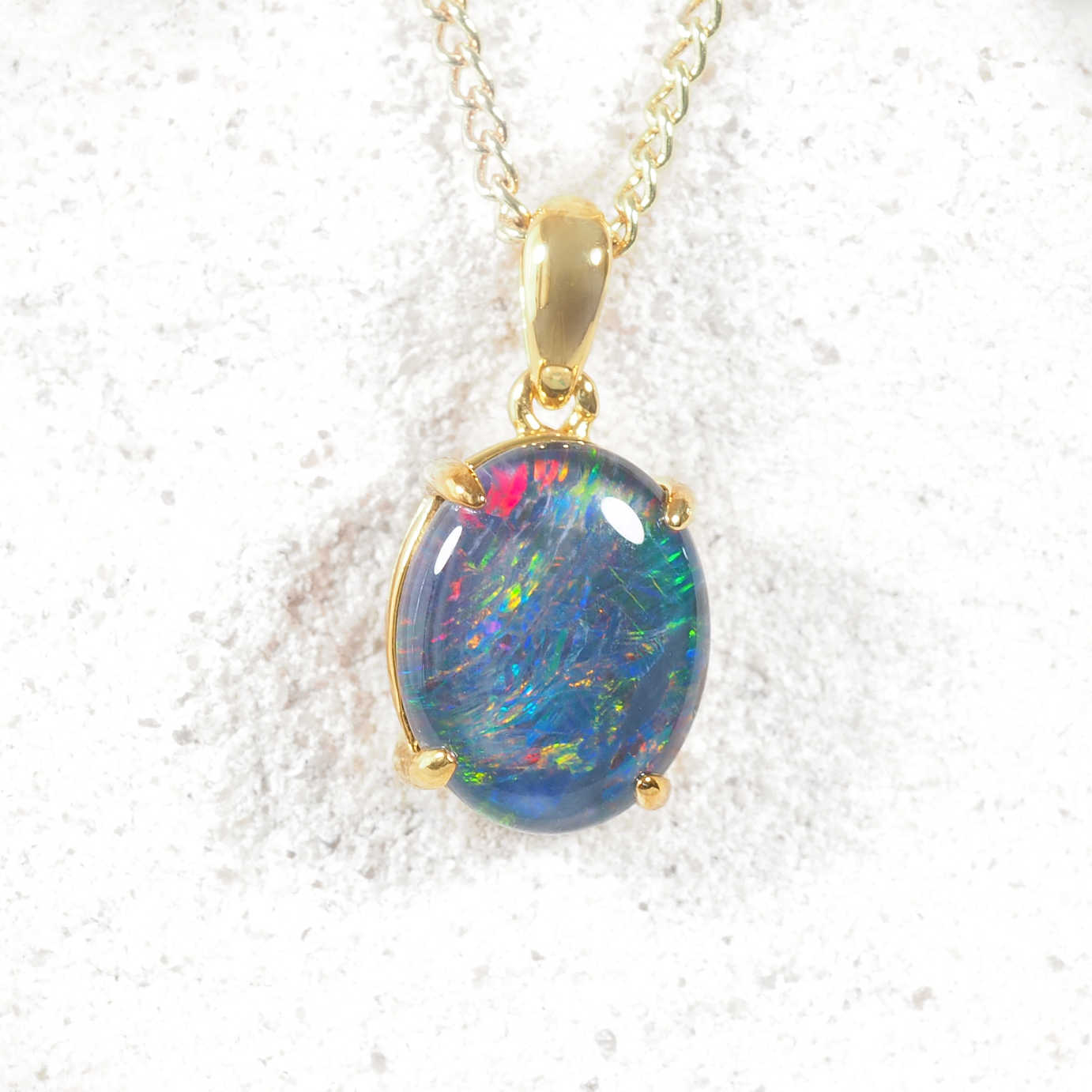 Opal pendant on a gold chain against a white background