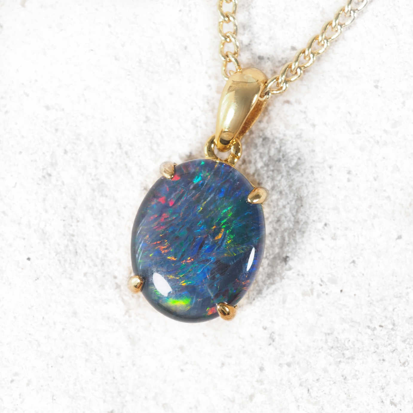 Gold plated opal pendant necklace on a white background