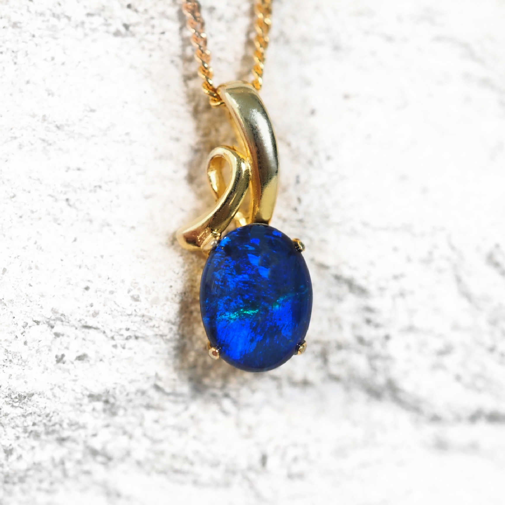 Gold-plated silver opal pendant necklace with blue-green Australian triplet opal in a decorative claw setting, on matching chain.
