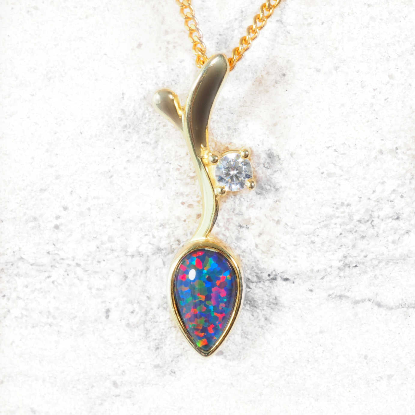 Gold opal pendant with a colorful gemstone on a white background