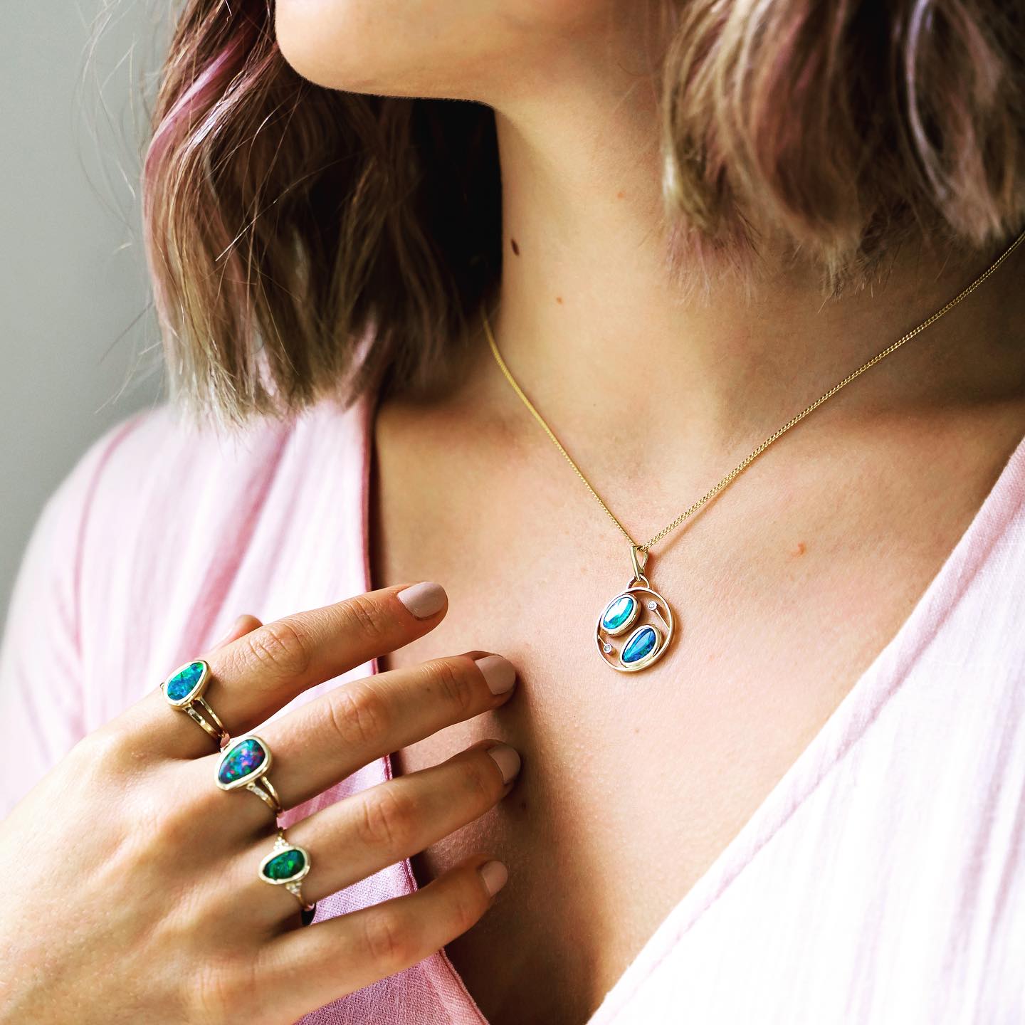 A model wearing opal rings on three fingers and an opal necklace around her neck