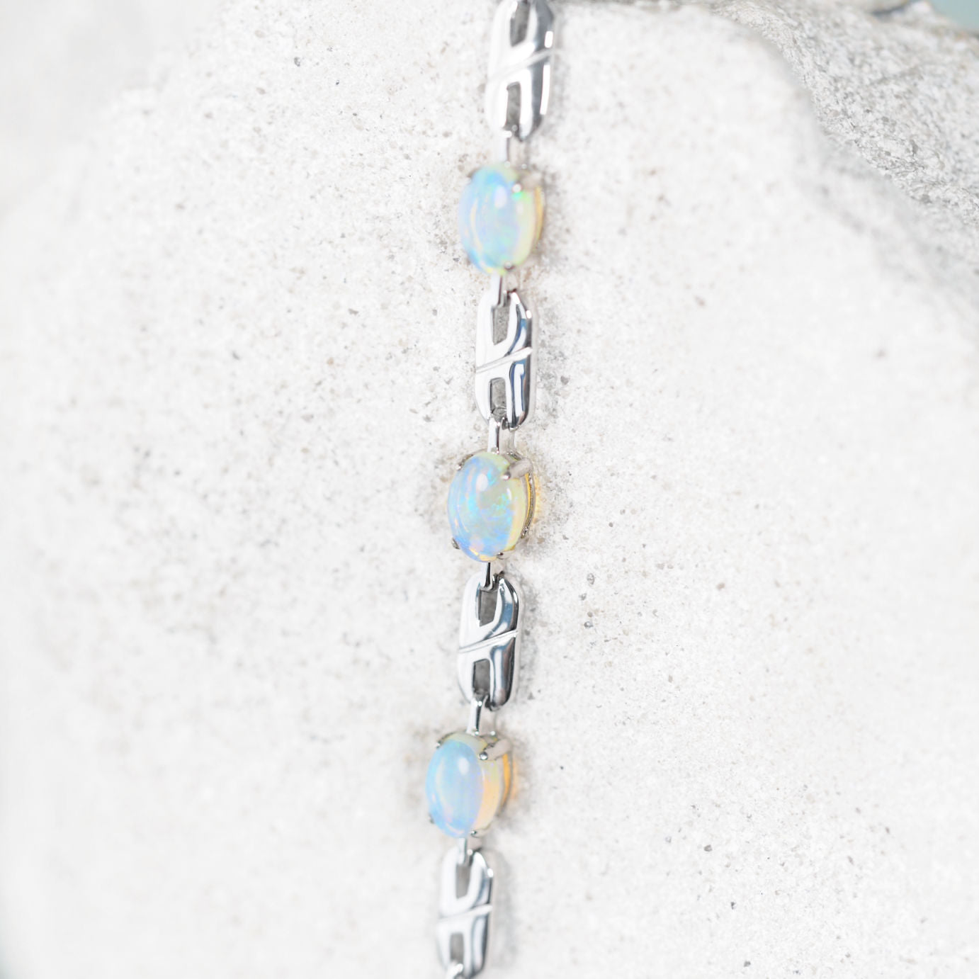 Silver bracelet with solid Australian opal stones on a textured white surface