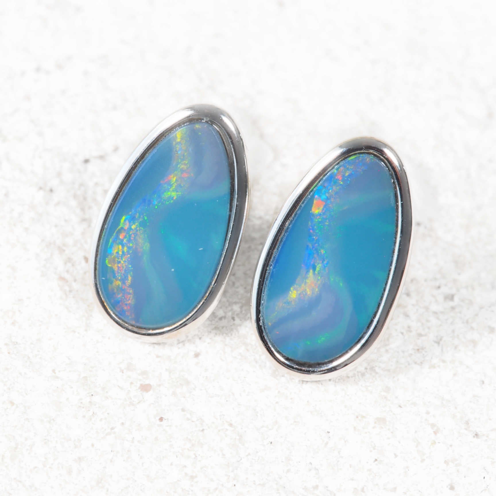 Opal earrings with silver setting on a textured white background