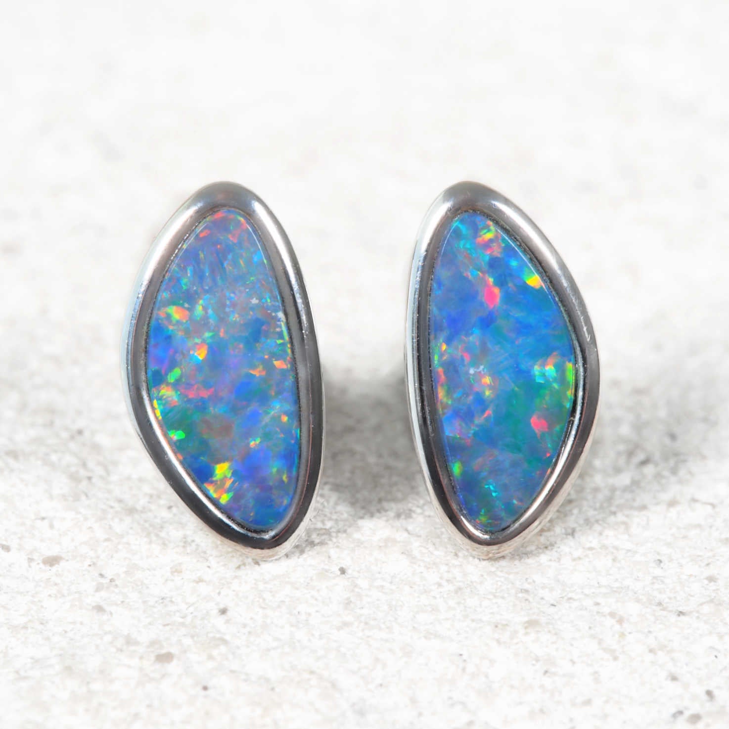 Pair of opal stud earrings with silver setting on a white background