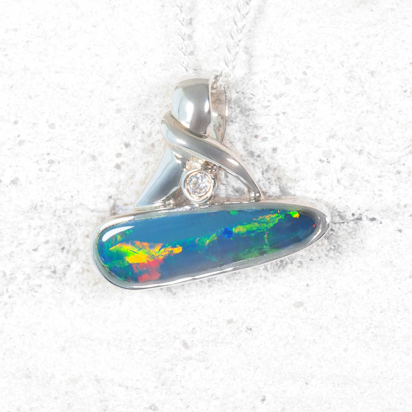 Opal pendant with silver setting on a textured white background