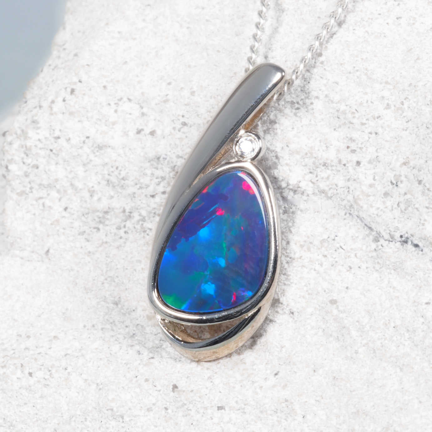 Opal pendant necklace on a textured white surface