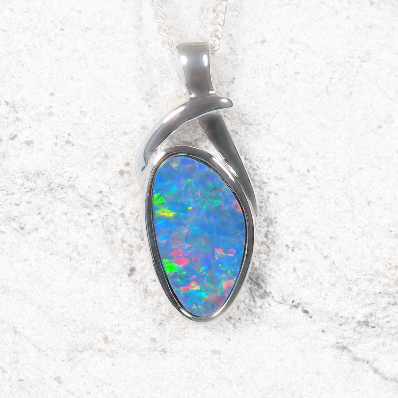 Opal pendant in a silver setting on a textured white background