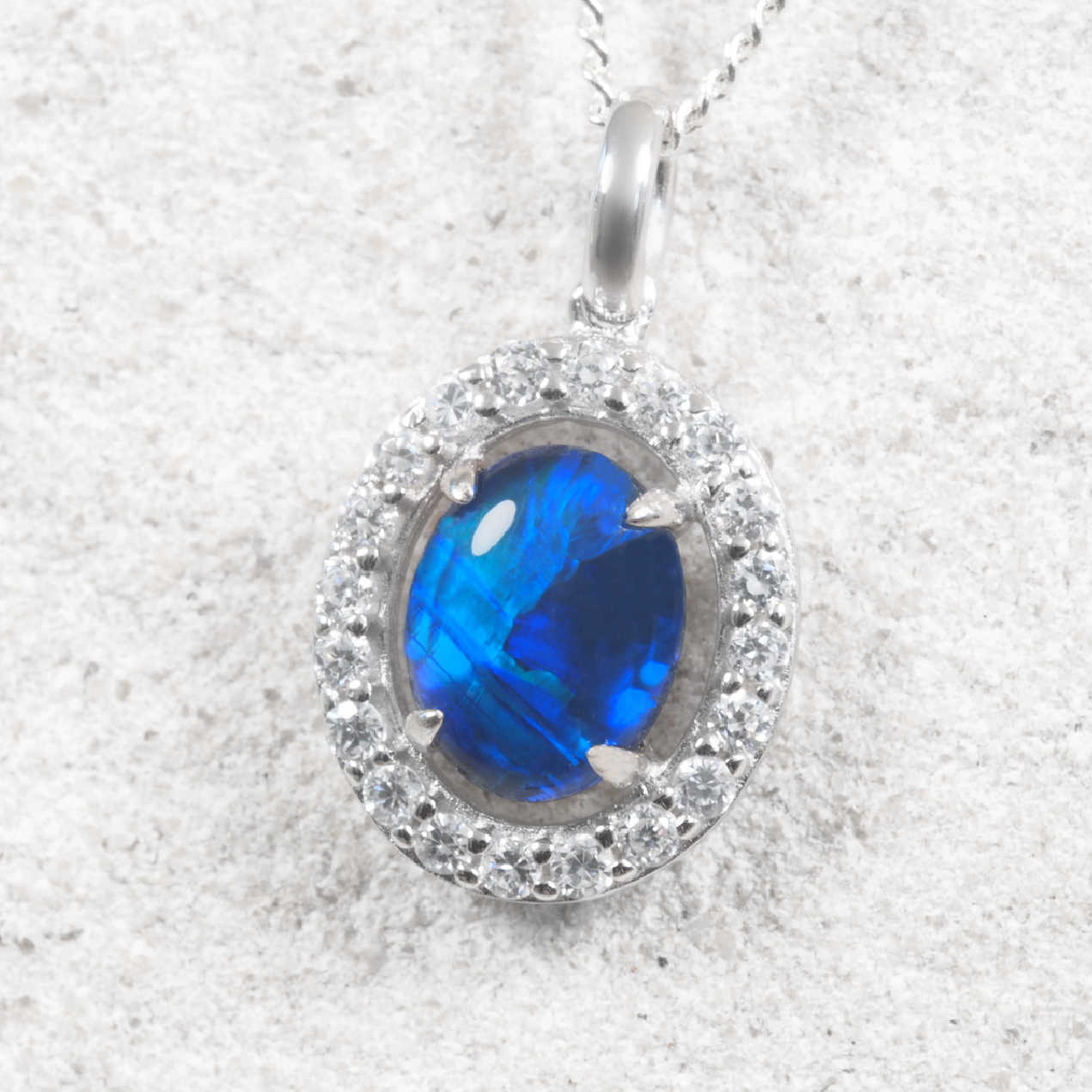 Australian blue opal necklace in polished sterling silver with an oval claw-set opal displaying vibrant ocean-blue and green play-of-colour.