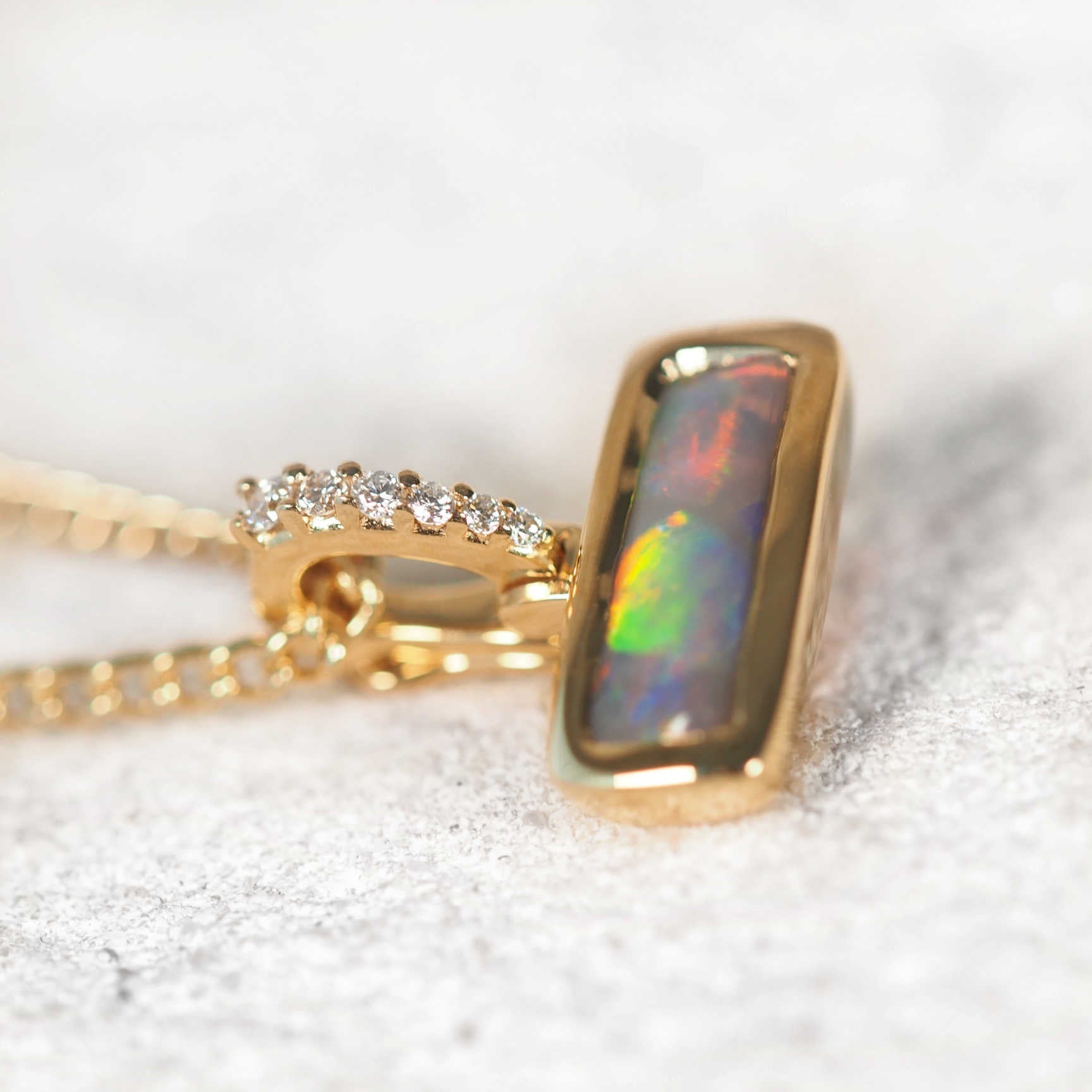 Rectangular Lightning Ridge black opal pendant in yellow gold with enhancer clasp