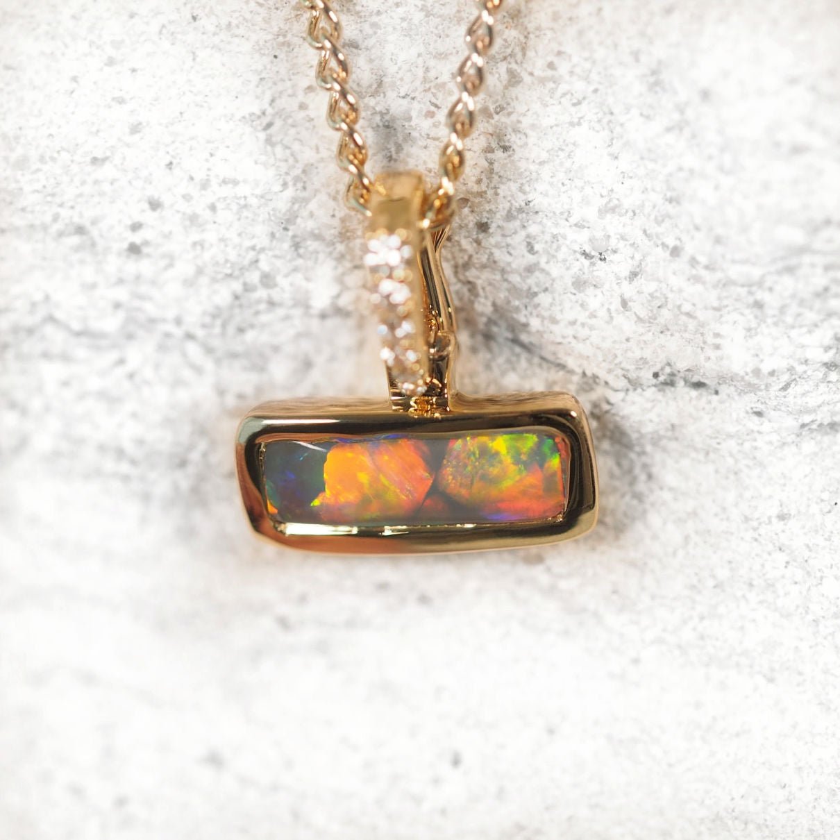 Gold pendant with opal stone on a white background