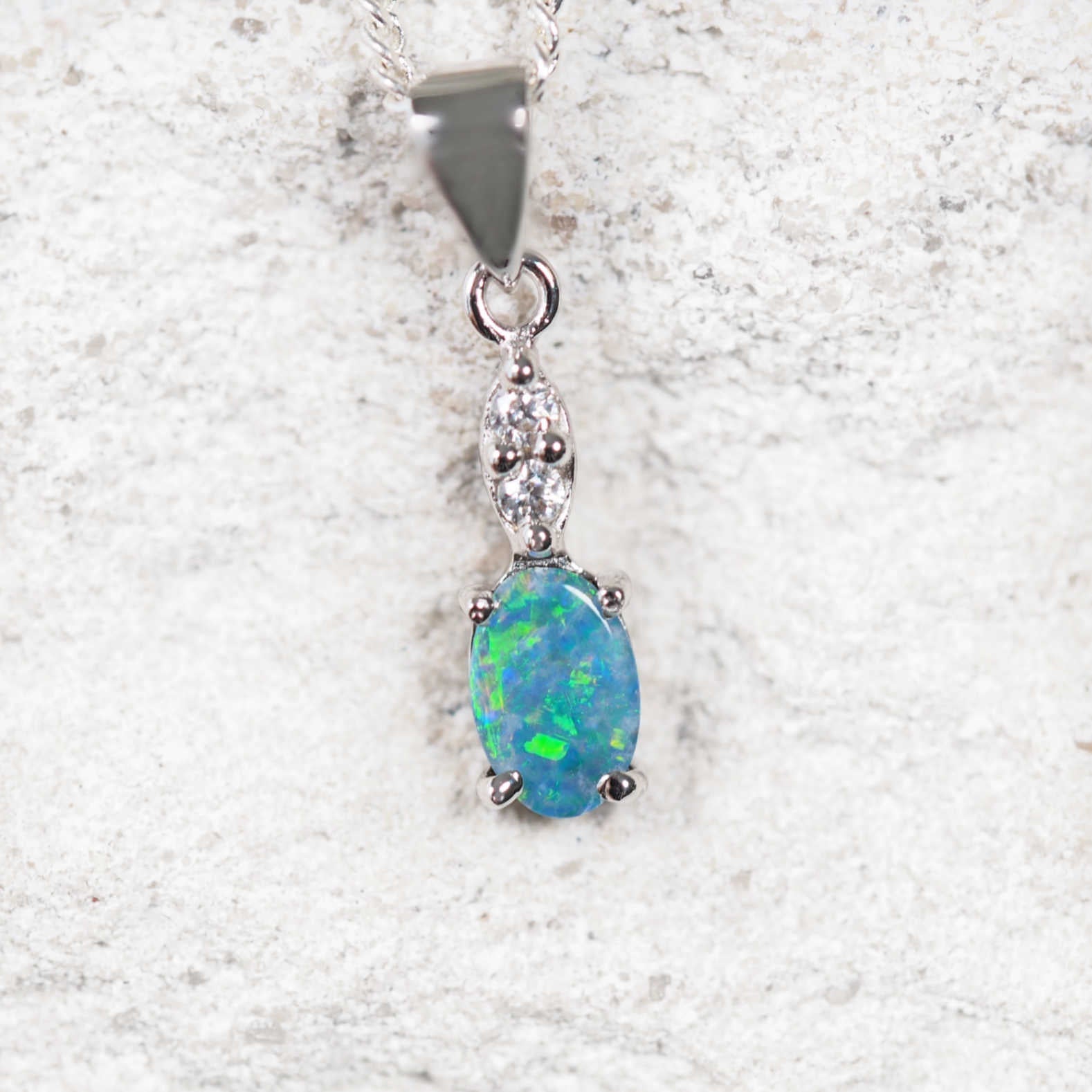 Sterling silver opal necklace featuring an oval blue and green Australian doublet opal with two cubic zirconias