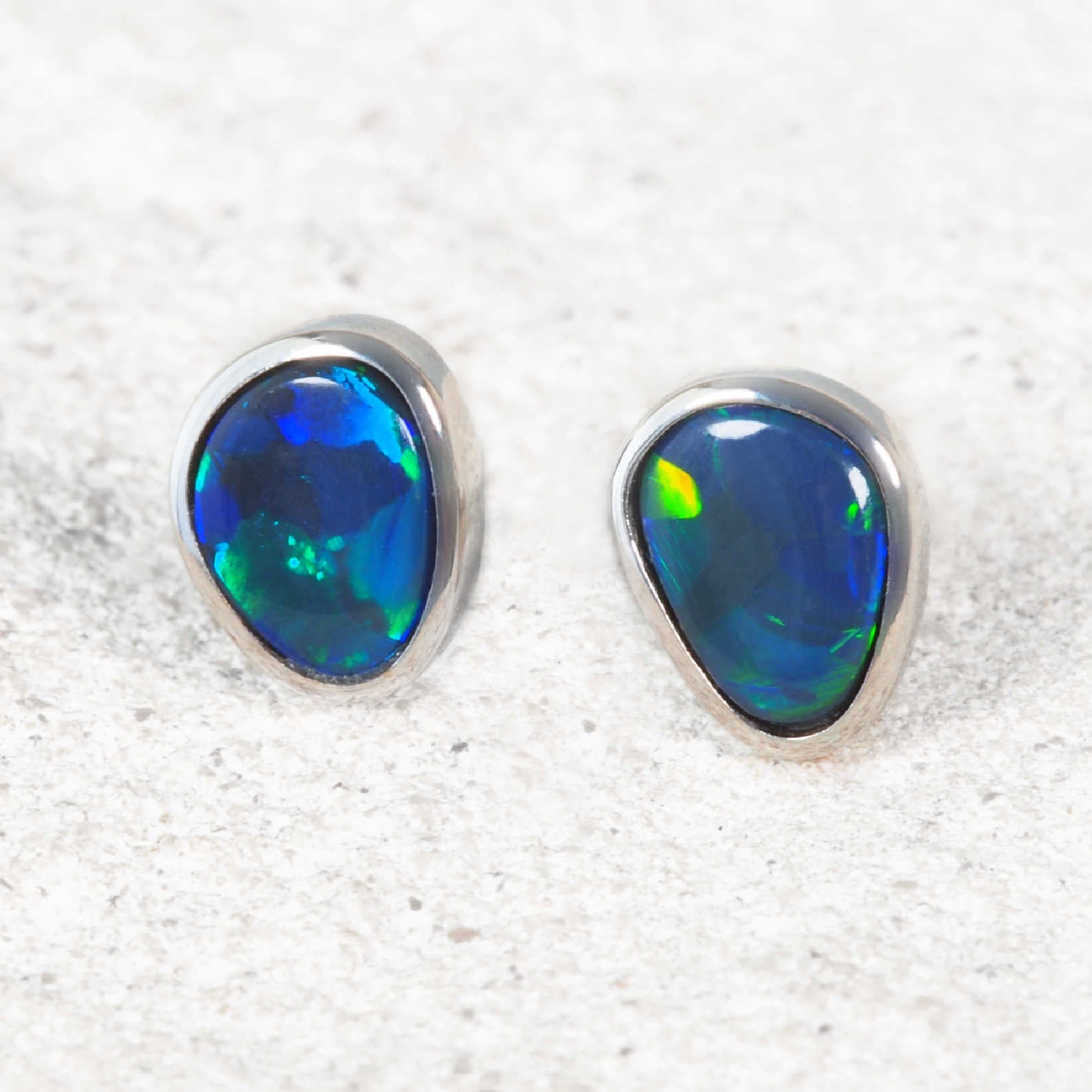 18ct white gold earrings with pear-shaped Lightning Ridge black opals displaying green and blue colour
