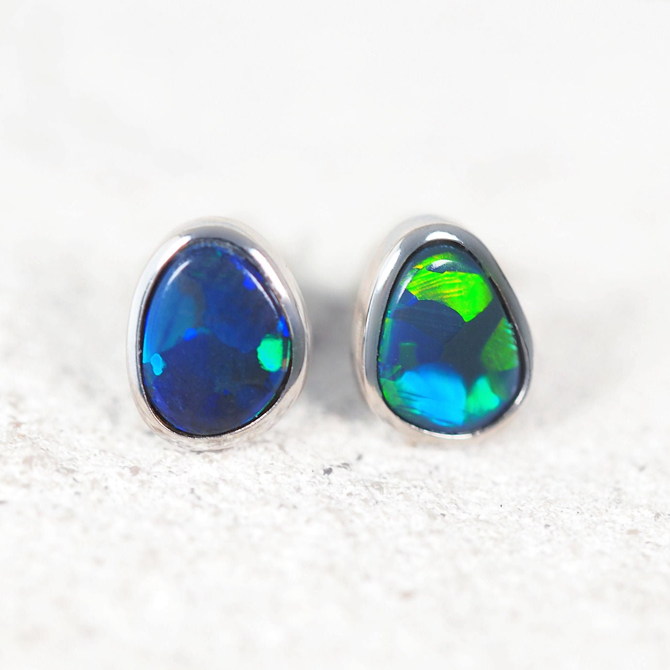 Pair of black opal stud earrings on a white background