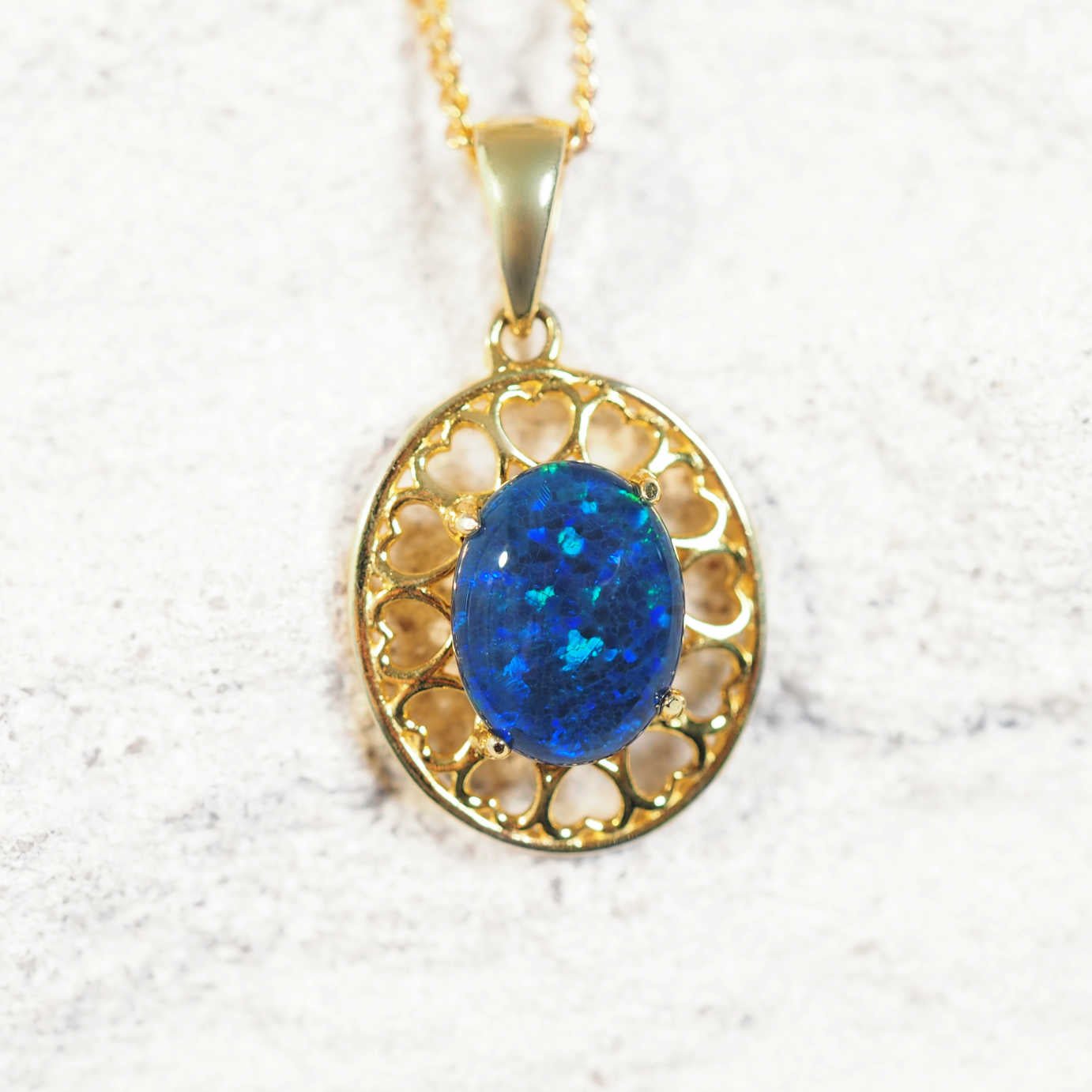 Gold pendant with a blue opal stone on a white background