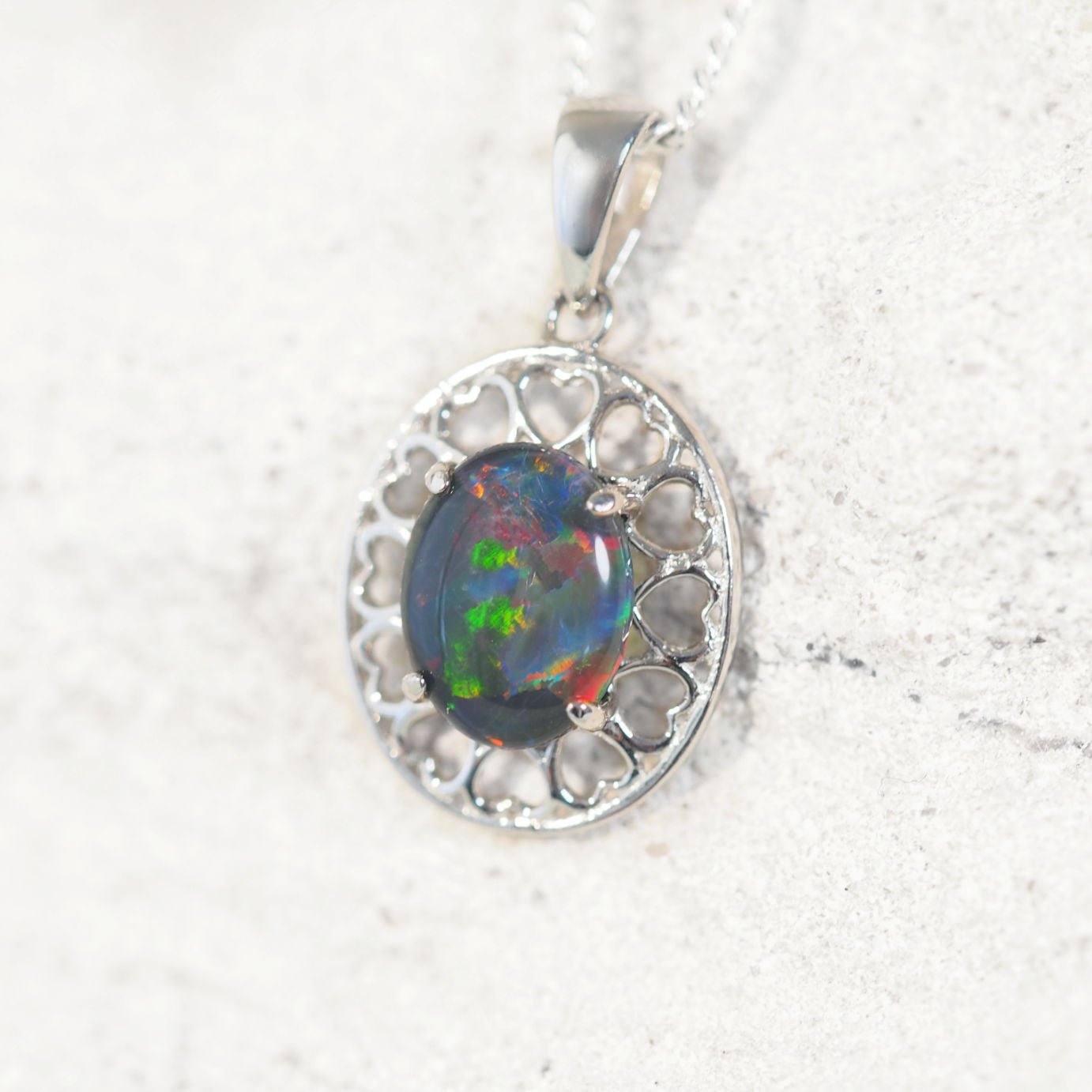 'Amore' opal pendant in sterling silver with decorative heart-pattern design and claw-set oval Australian triplet opal in vibrant multi-coloured tones