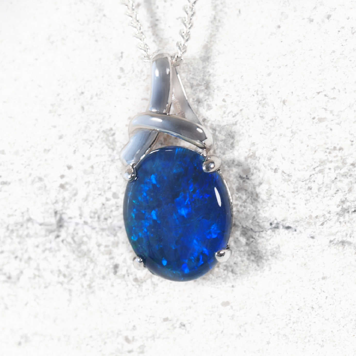 Blue opal pendant on a silver chain against a white background