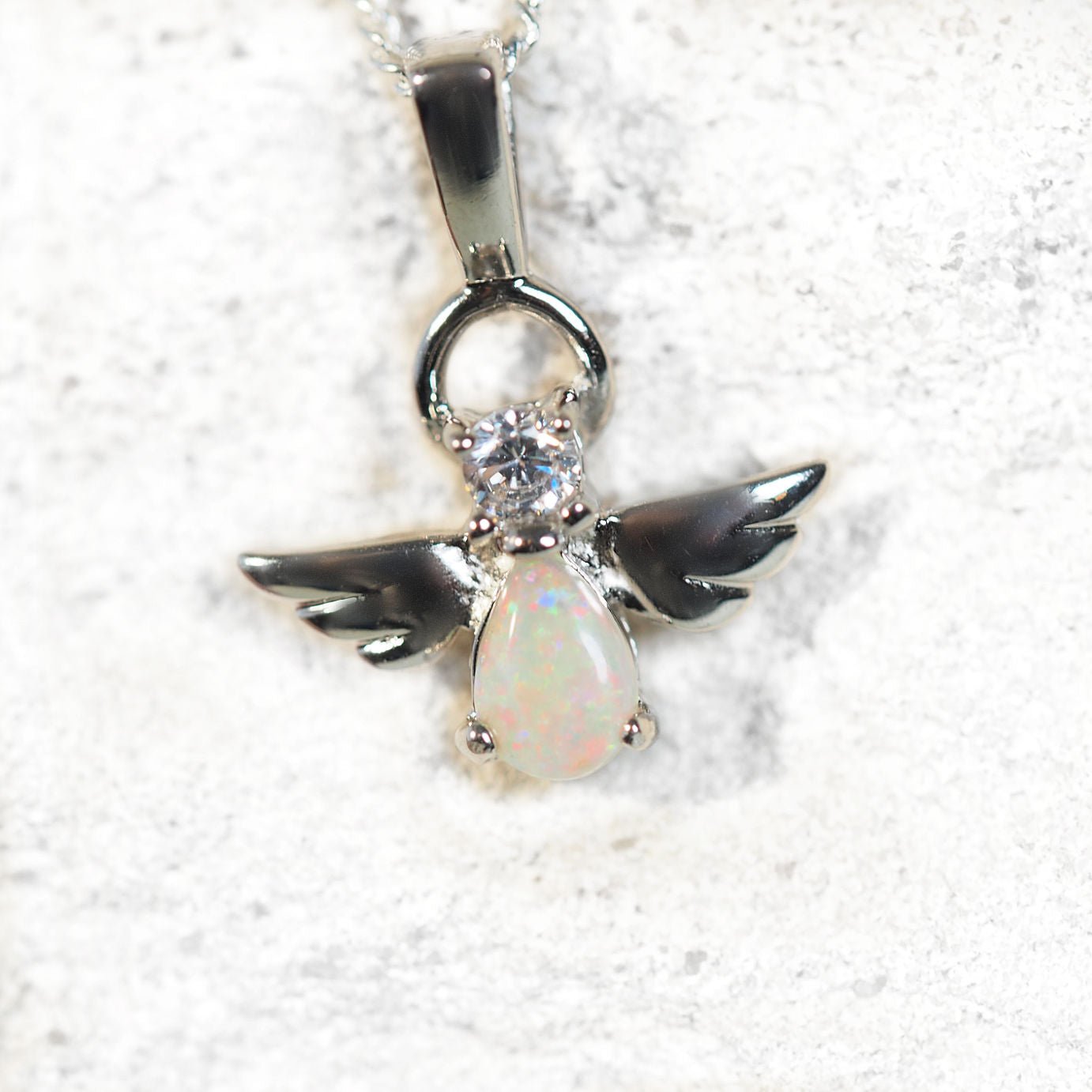 Angel pendant with opal gemstone on a white background