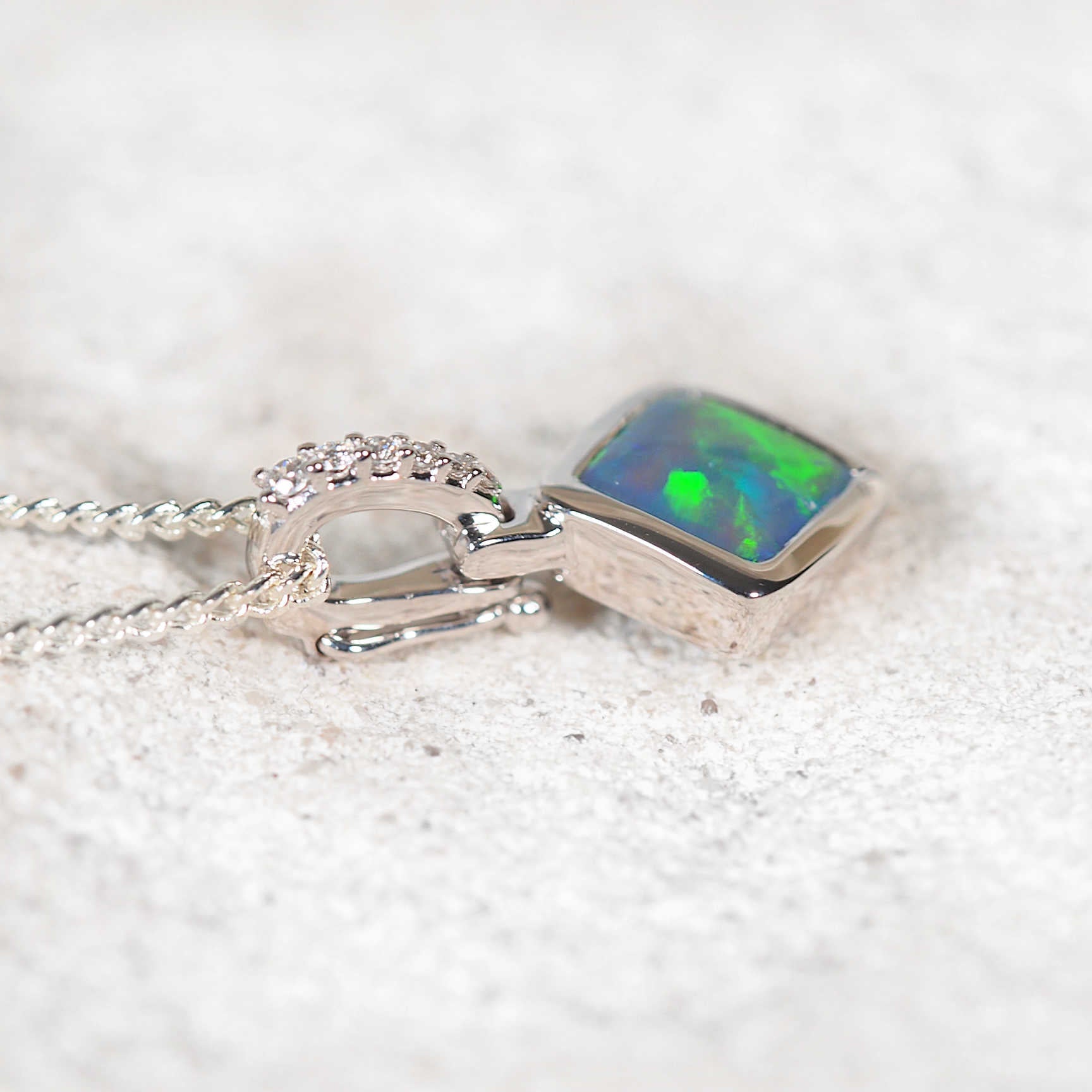 Luxury Australian black opal pendant in 14ct white gold, featuring vivid neon-green opal and six sparkling diamonds