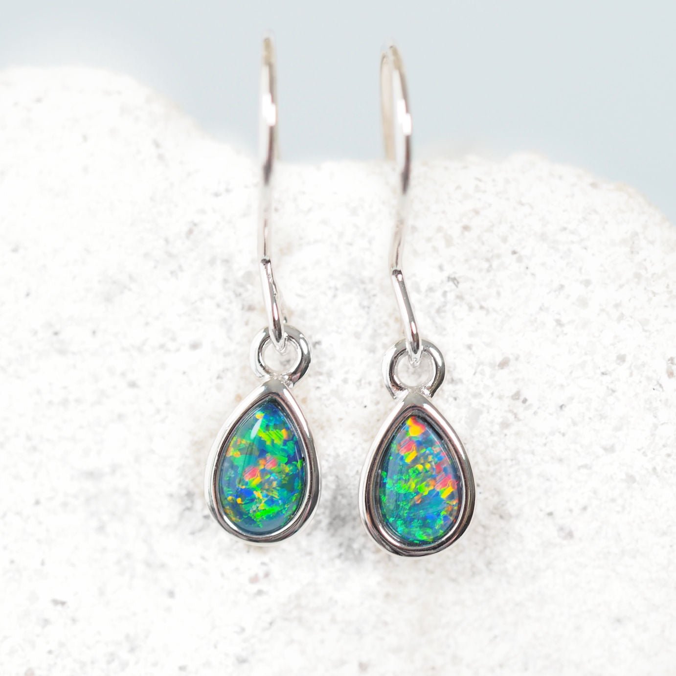 Teardrop-shaped opal earrings on a white background