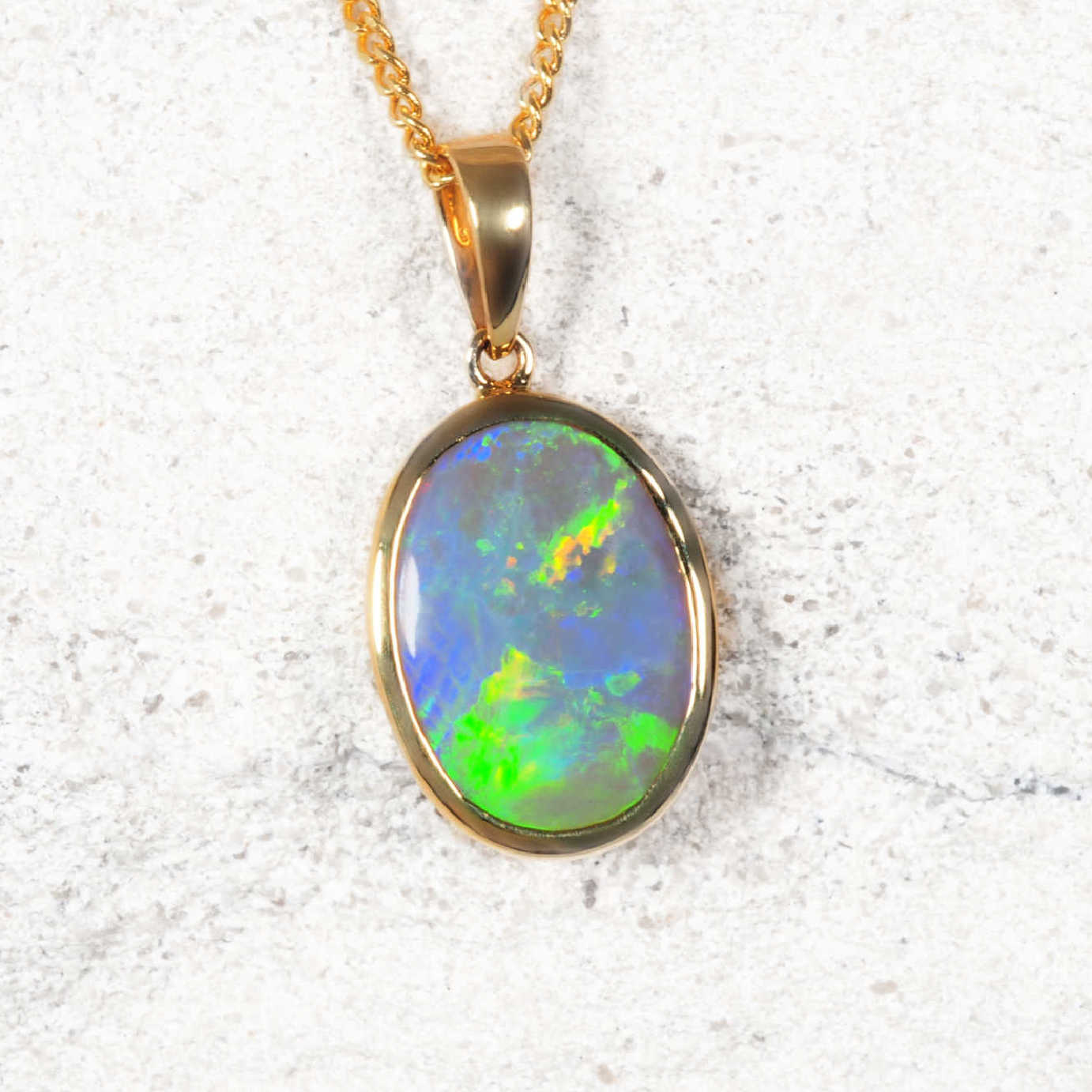 Lightning Ridge opal pendant necklace on a gold chain against a white background