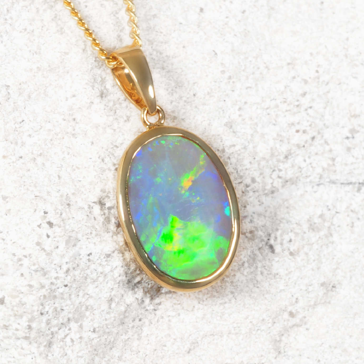 Genuine opal pendant with gold frame on a textured white background