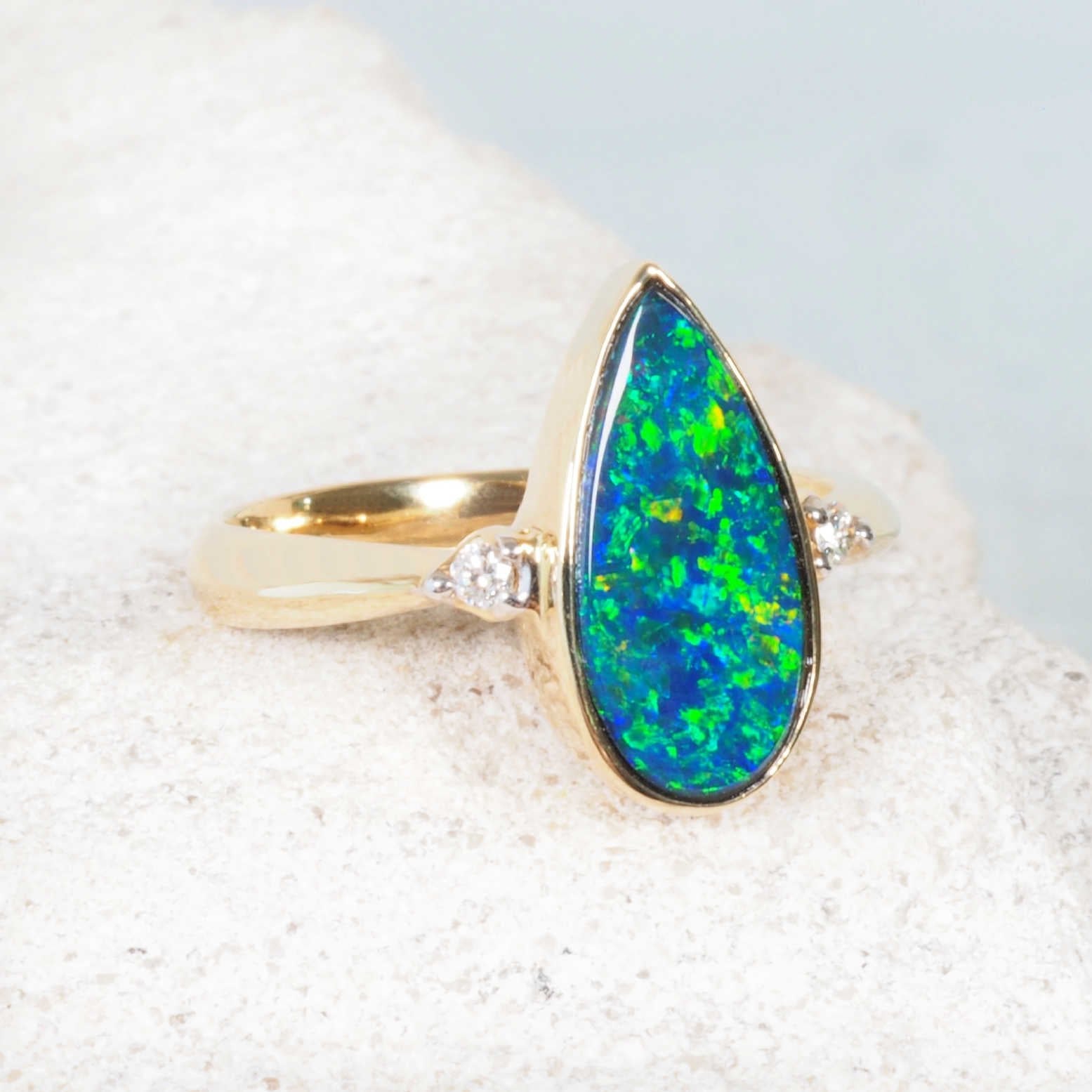 Elegant green and blue opal ring with red fire and two shoulder diamonds