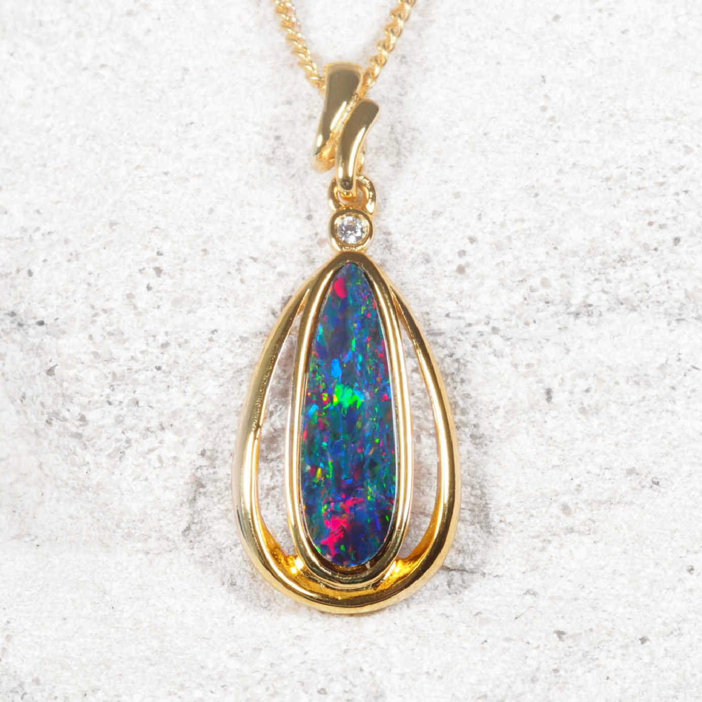 Opal pendant with gold frame on a textured white background