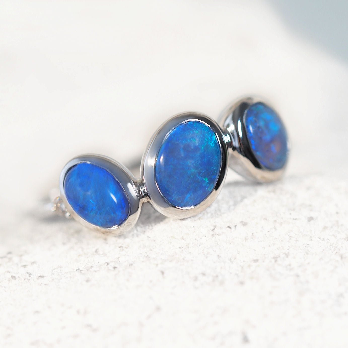 White gold black opal gemstones on a textured white surface