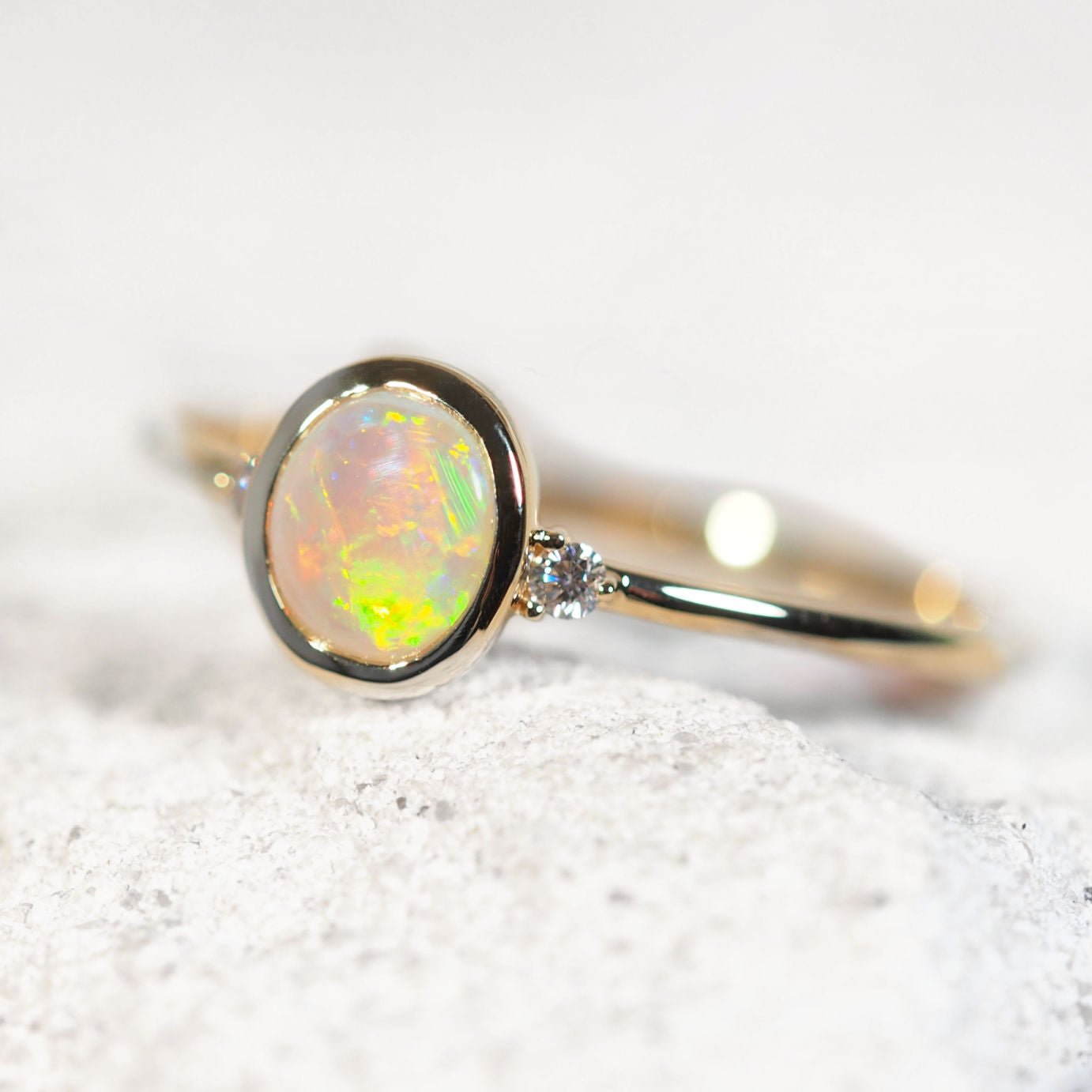 Opal ring with gold band on a textured white surface