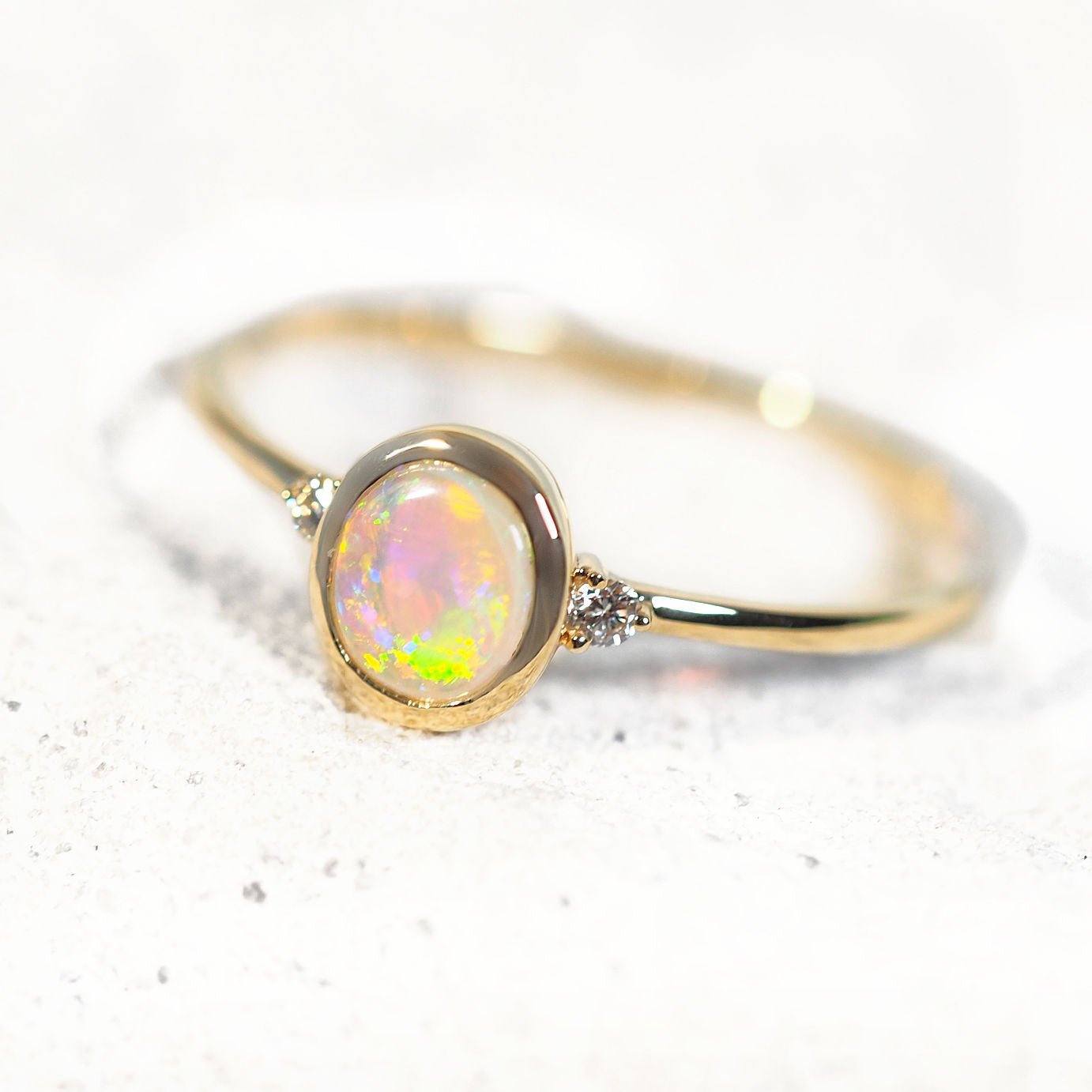 Gold ring with a colorful opal gemstone on a light background