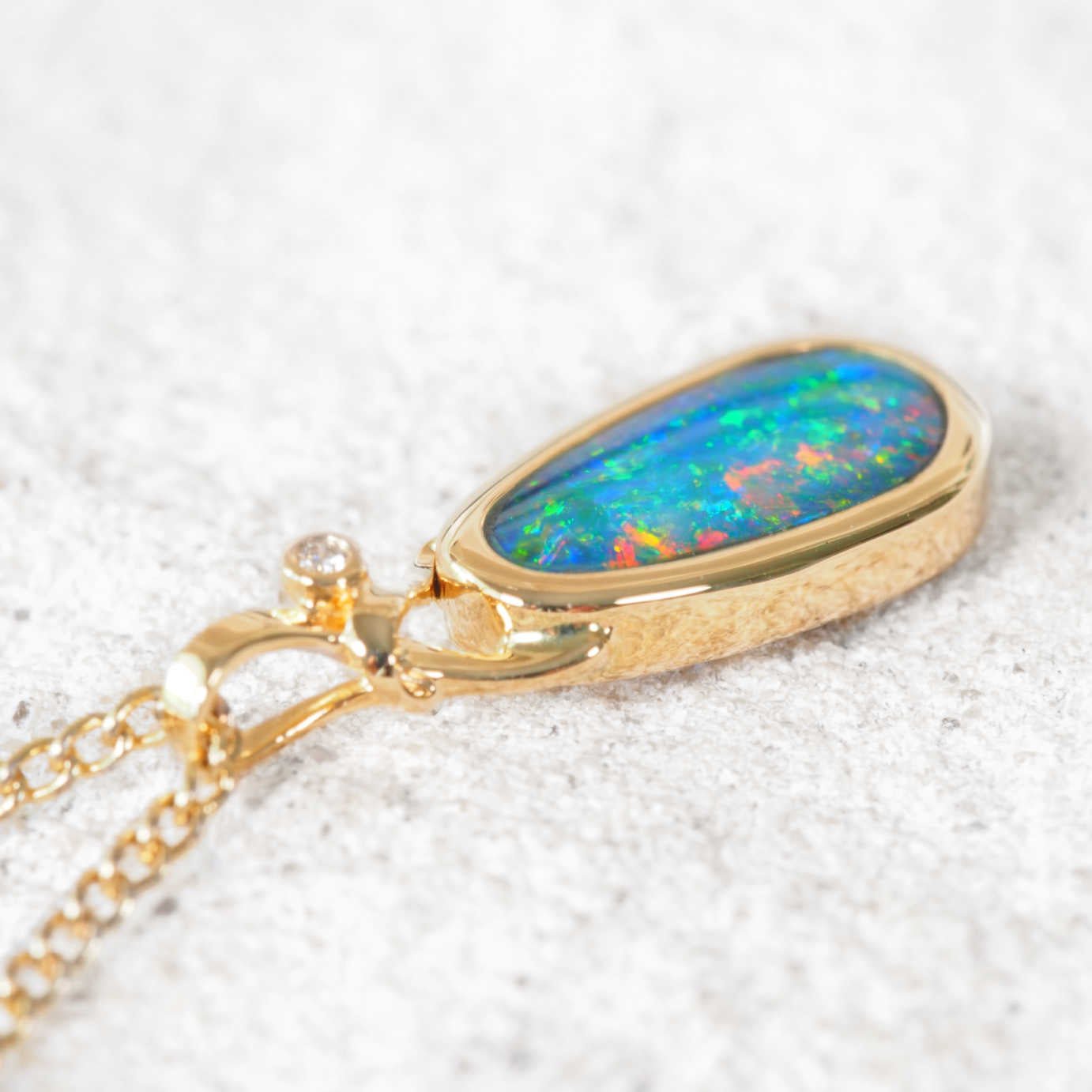 Gold opal necklace with an colourful doublet opal on a white background