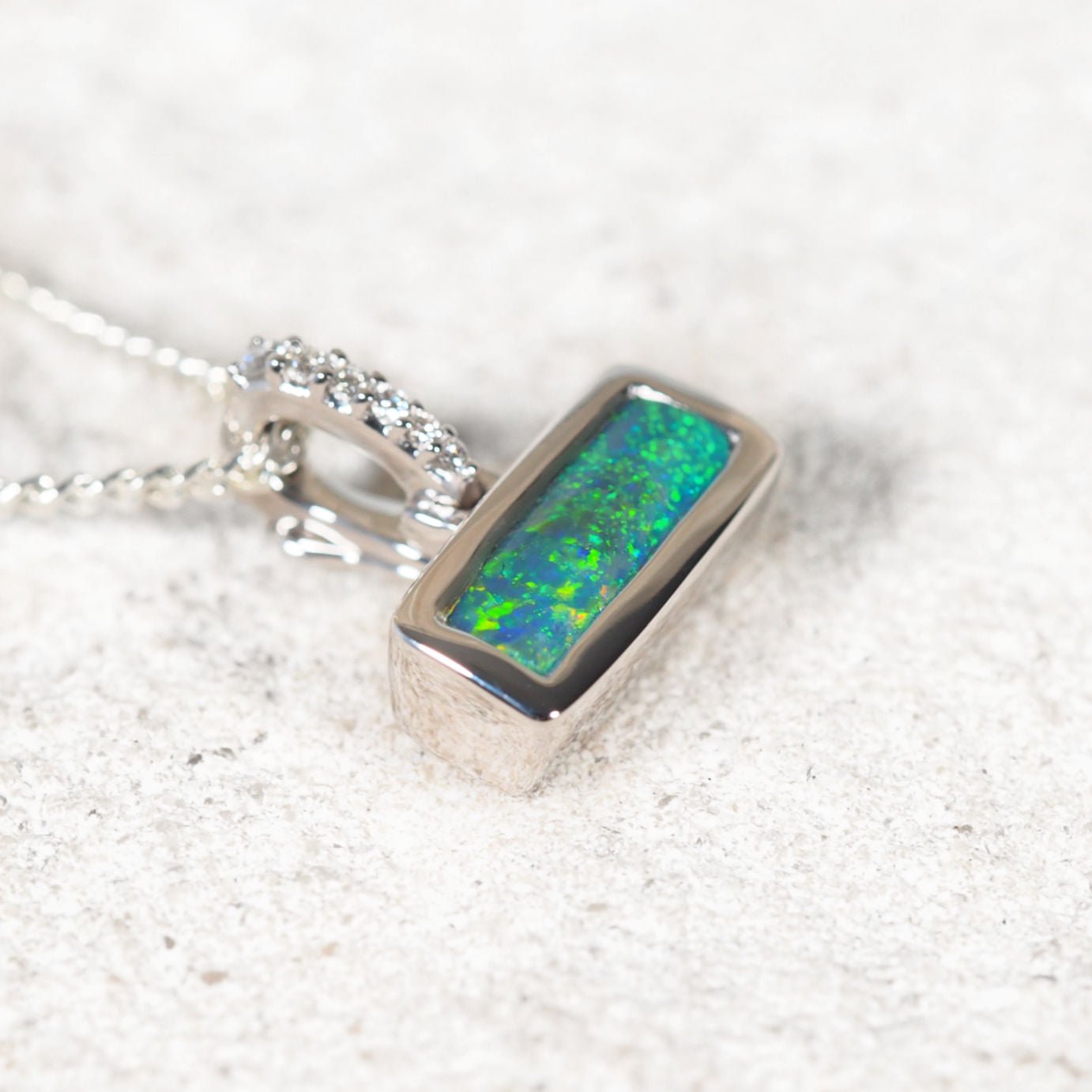 Rectangular Lightning Ridge black opal pendant showing vivid floral pattern and multi-colour fire in white gold setting