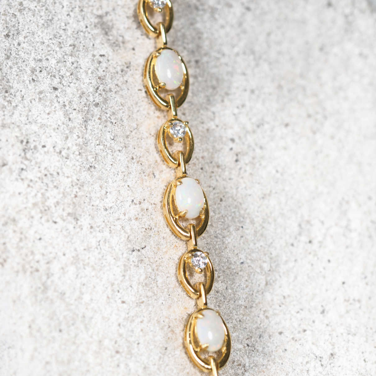 Gold plated opal bracelet with crystals on a textured beige background