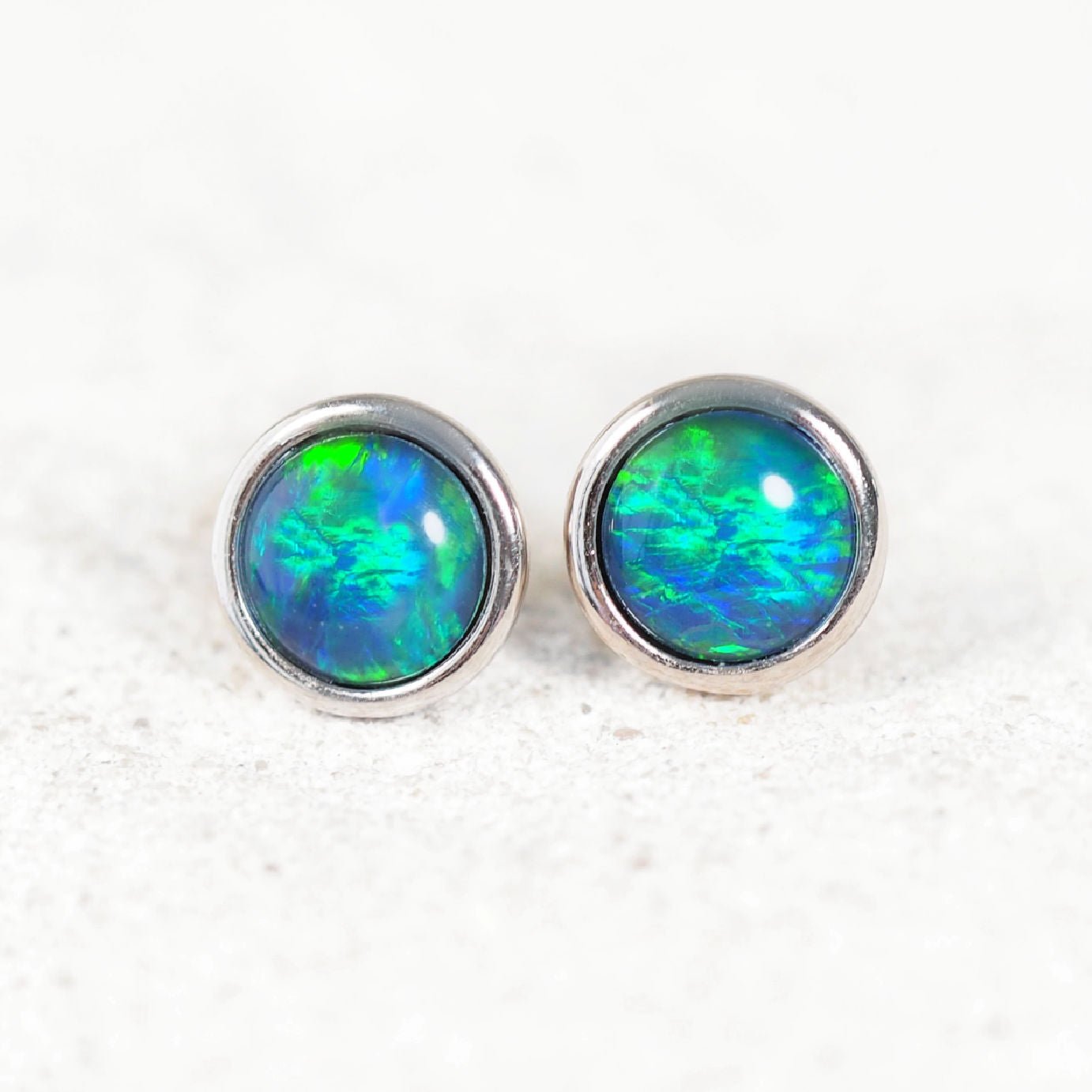 Opal stud earrings with silver setting on a white background