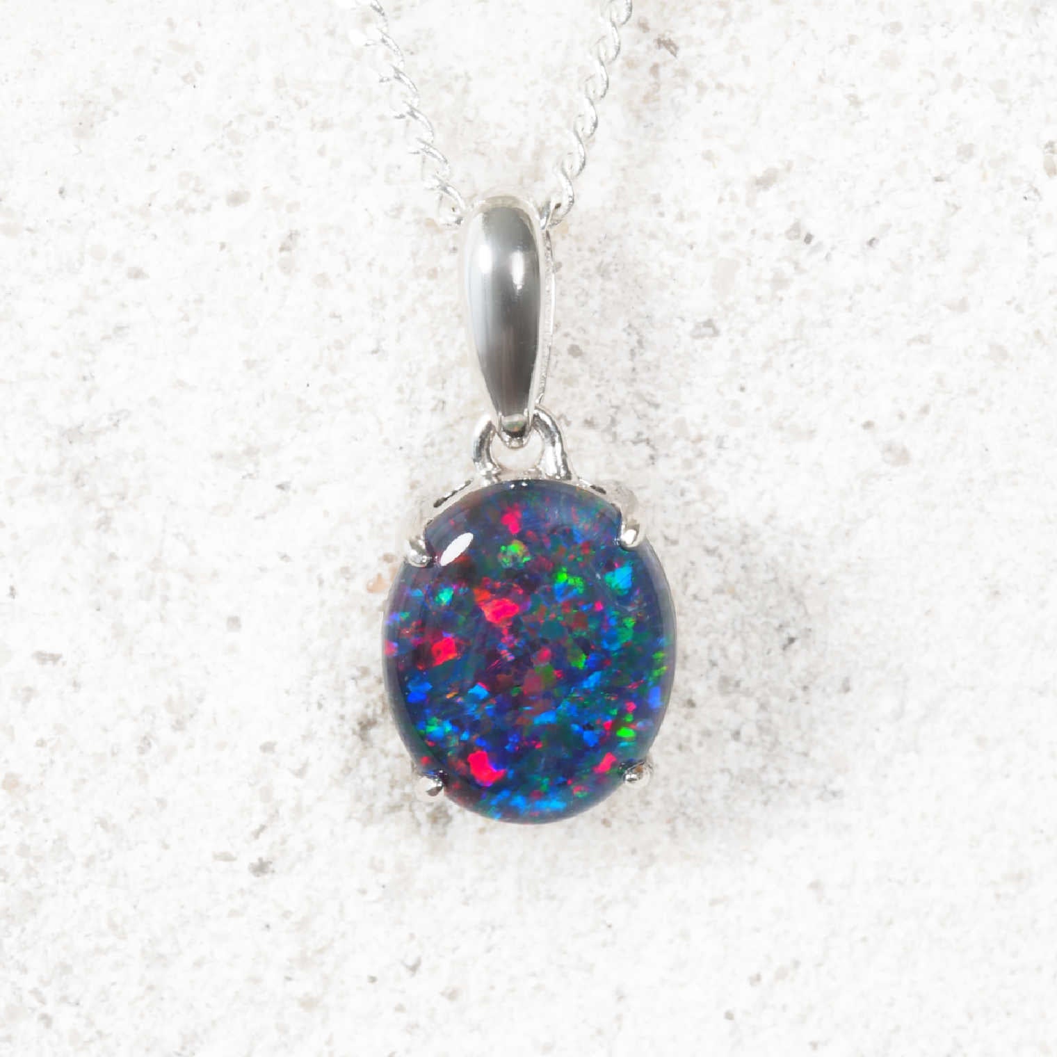 Opal pendant on a silver chain against a white background