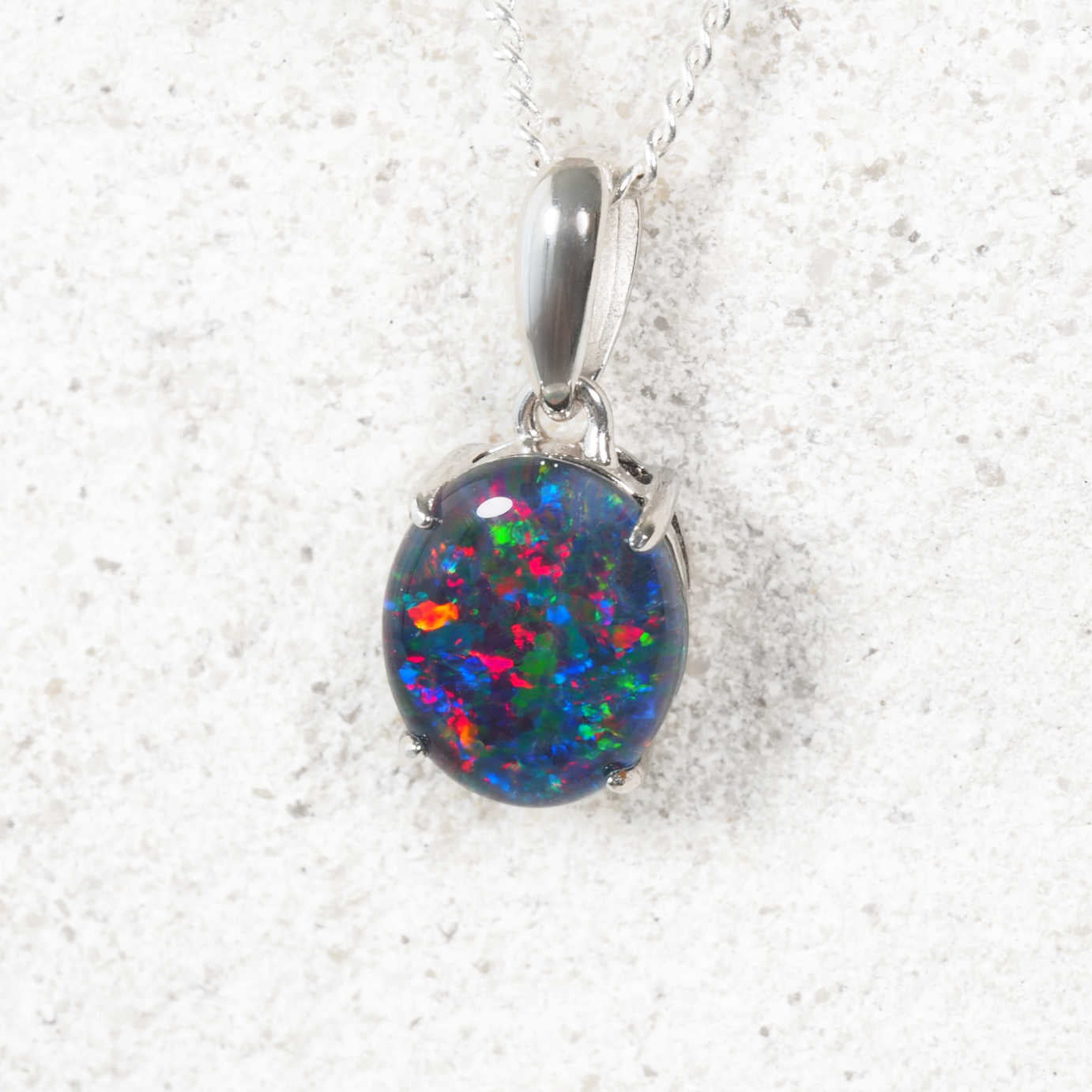 Triplet opal necklace on a silver chain against a white rock background