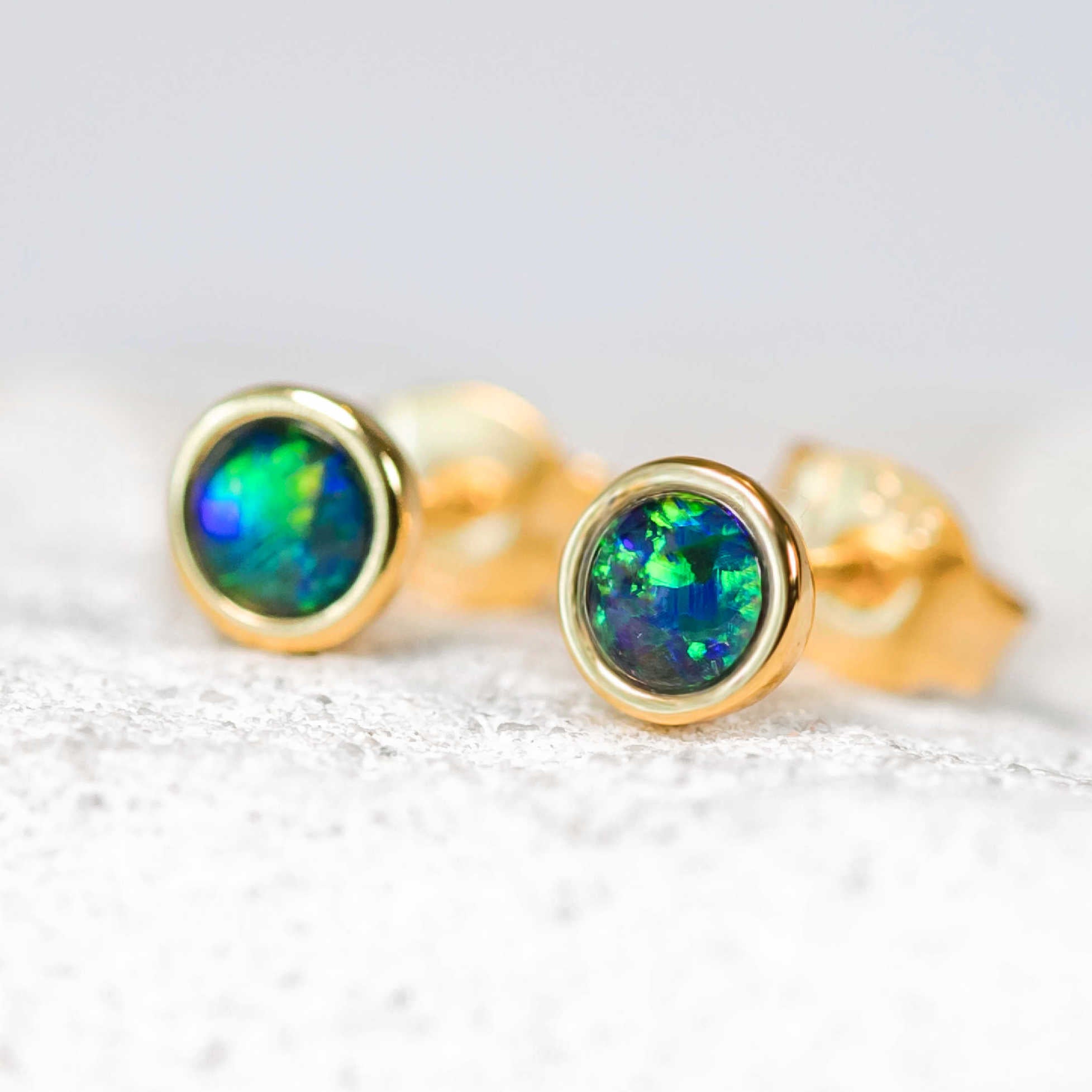 Gold earrings with green opal stones on a white background