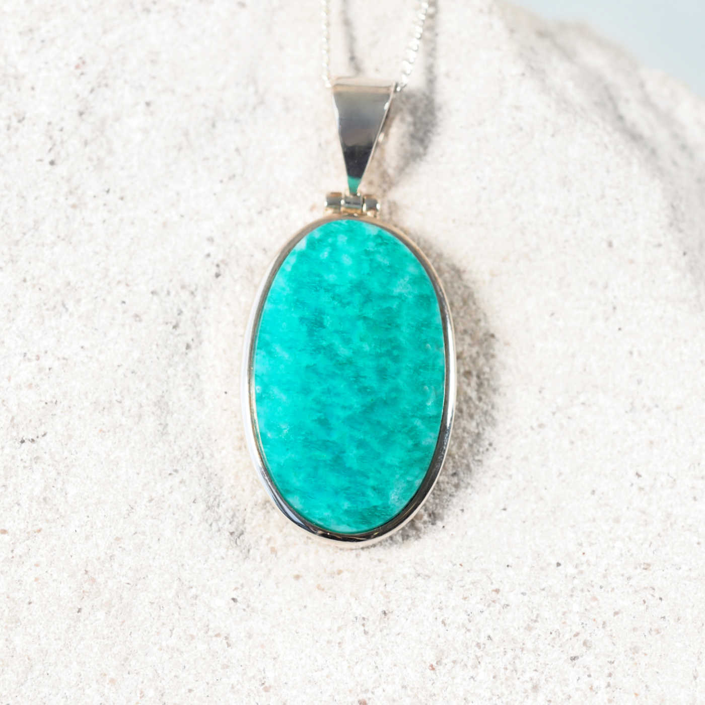 The 'Cleo' pendant showcasing an oval Amazonite cabochon set in a polished silver frame, highlighting its calming blue-green tones