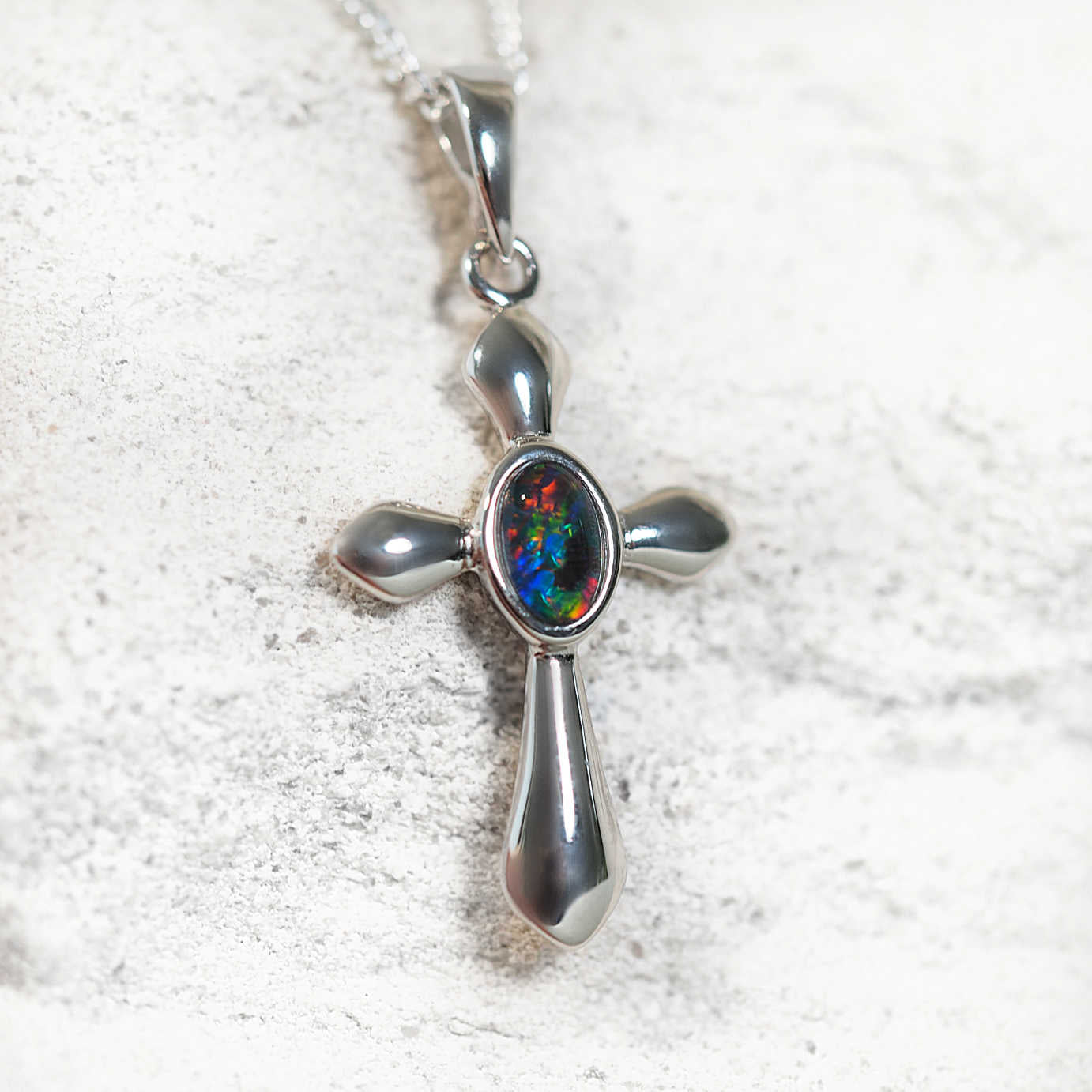Crucifix opal pendant in sterling silver with bezel-set oval Australian triplet opal in vibrant multi-coloured tones