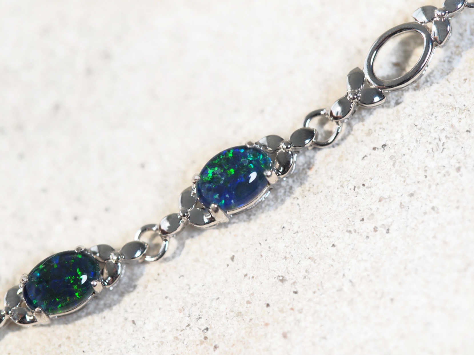 Silver bracelet with blue opal gemstones on a light gray background