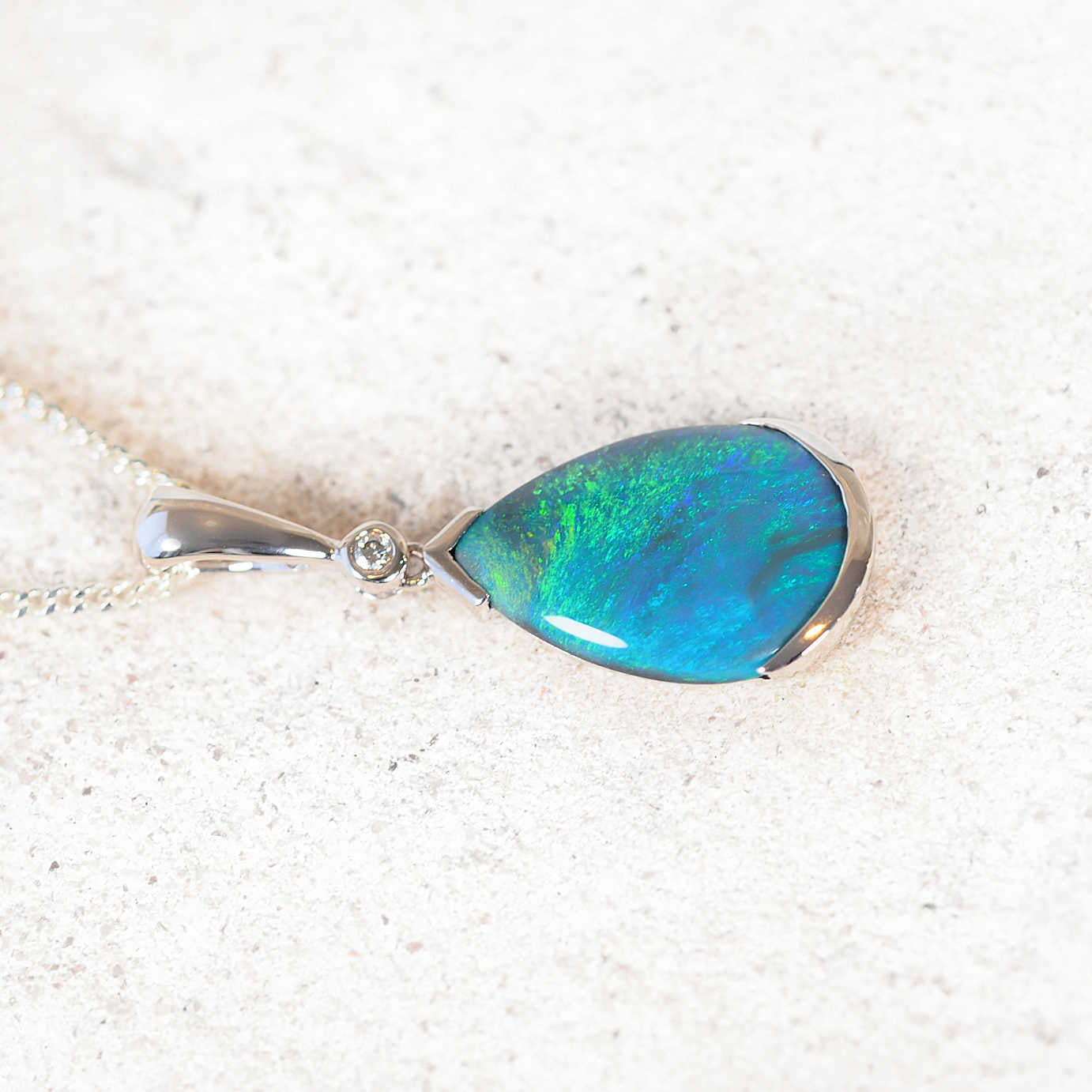 Luxury 14ct white gold necklace showcasing teardrop black opal with vibrant green-blue flashes and sparkling diamond