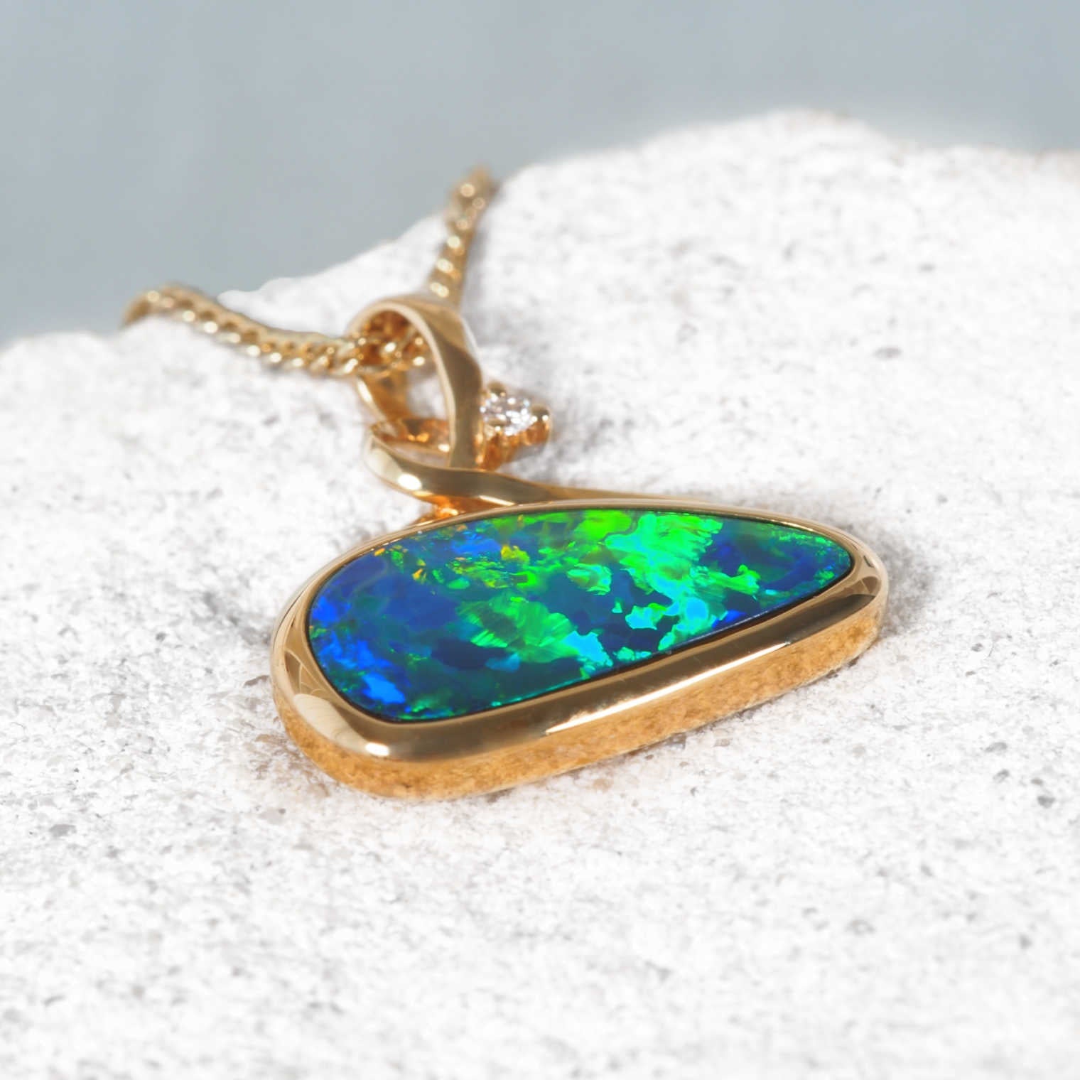 Close-up of Australian opal pendant in 14ct yellow gold with sparkling diamond