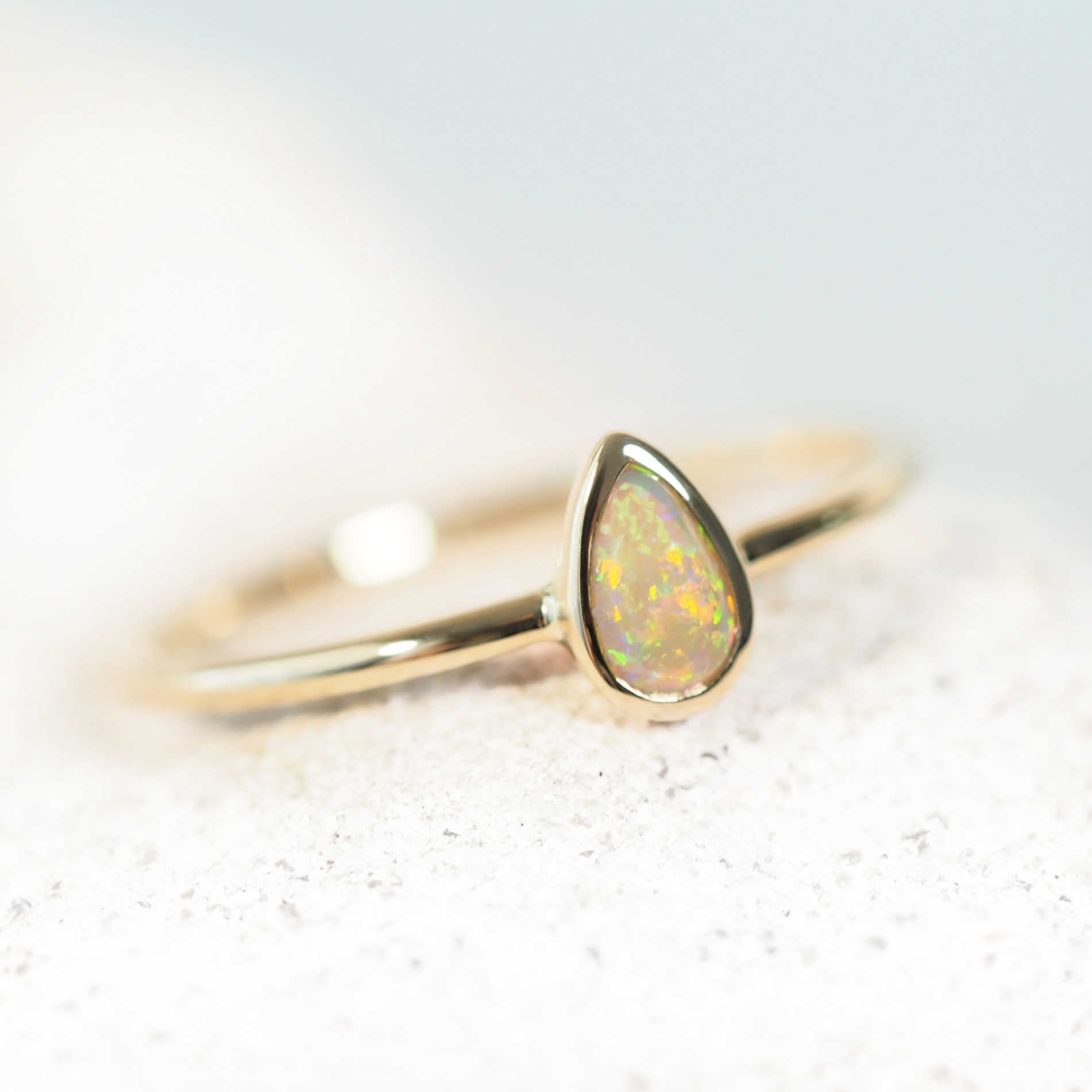 colourful opal ring set in yellow gold with a teardrop shape opal stone