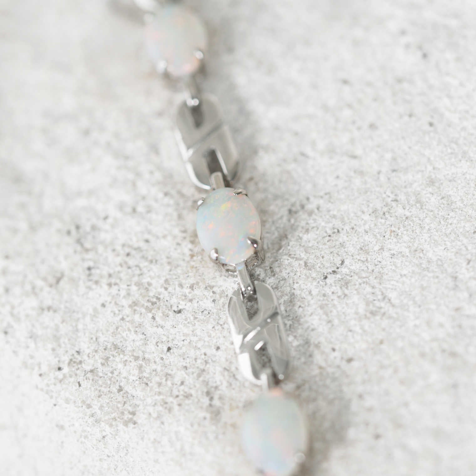 Silver bracelet with three opal gemstones on a textured white surface