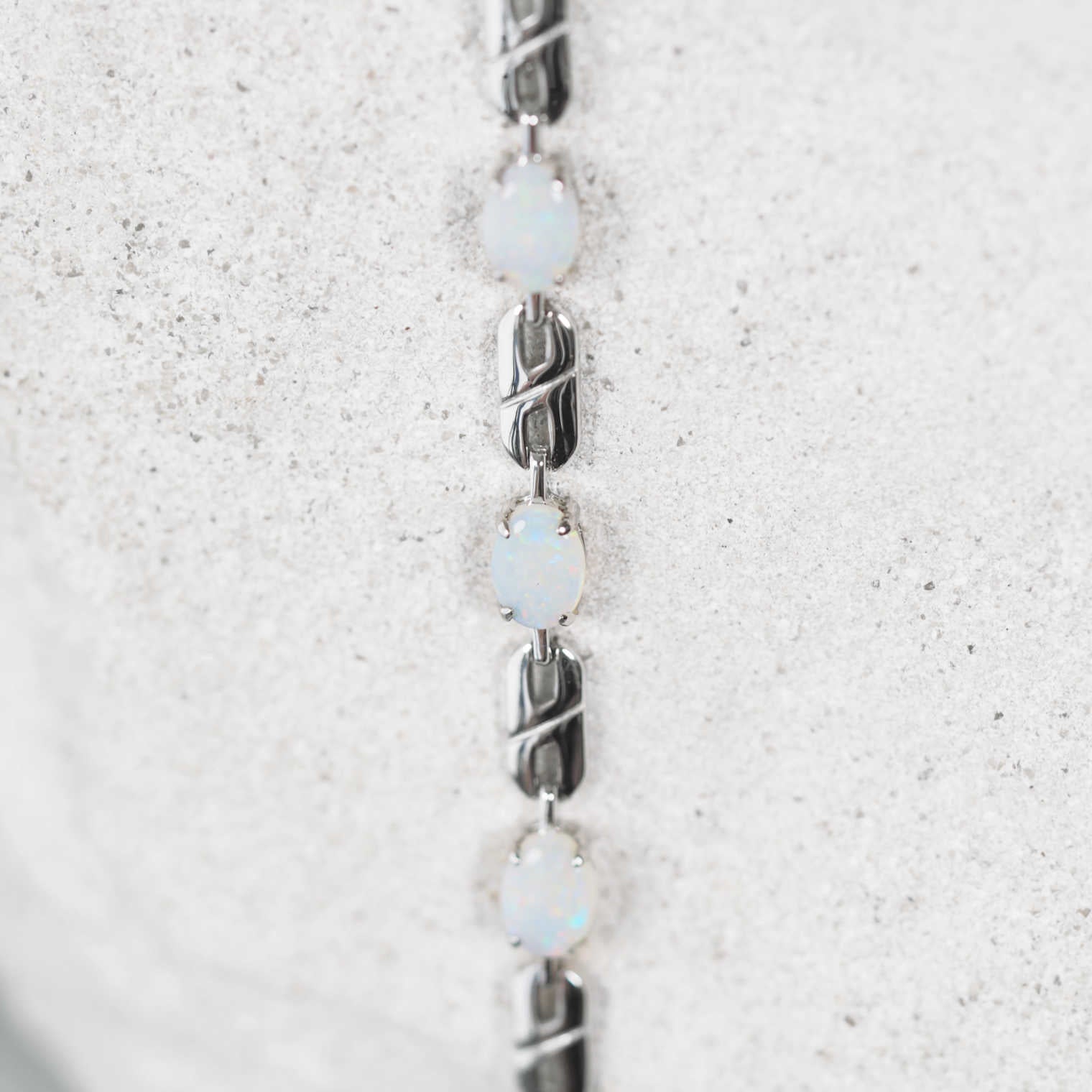 Silver bracelet with opal stones on a textured white background